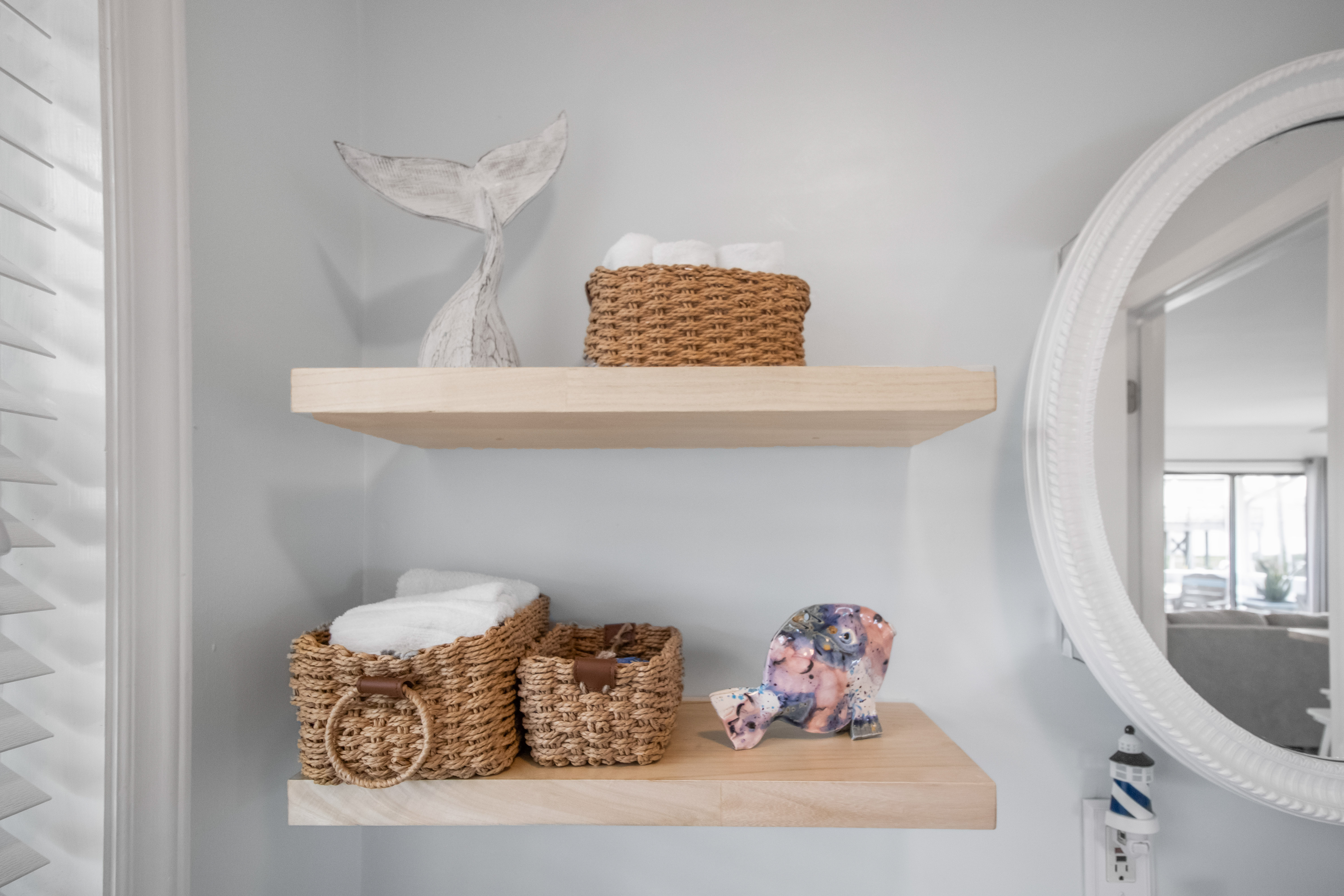 Stylish bathroom with floating shelves, plush towels, and coastal charm