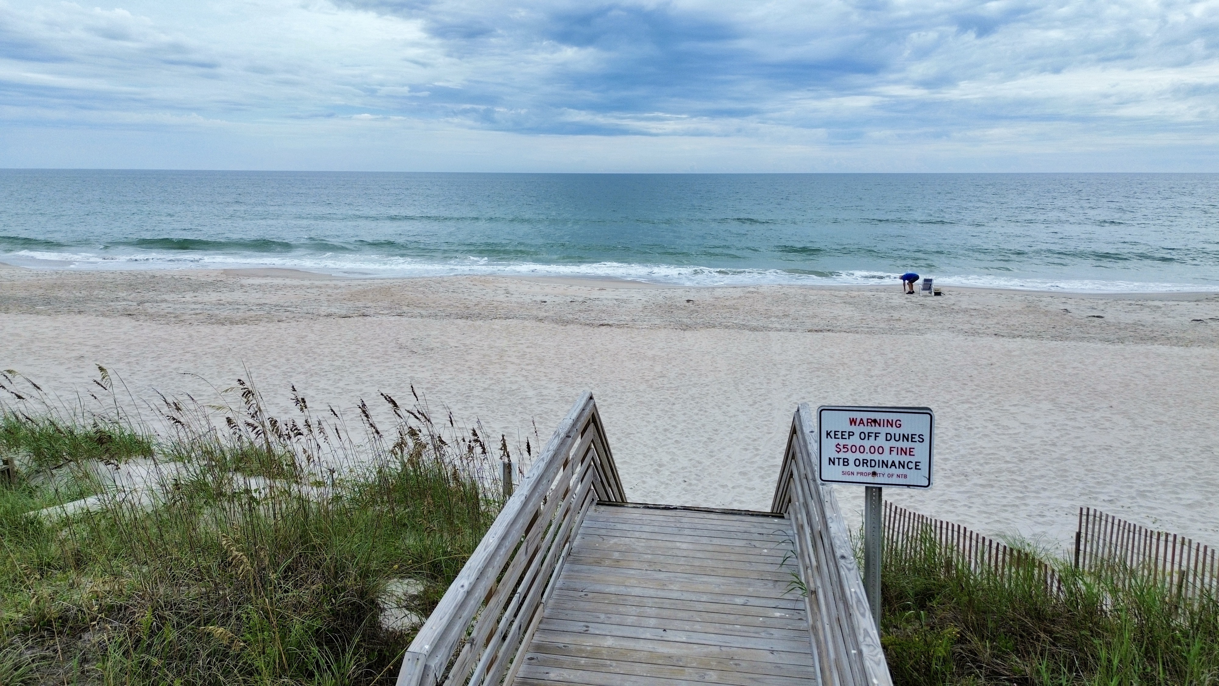 Private boardwalk access to a wide, peaceful beach with ocean views
