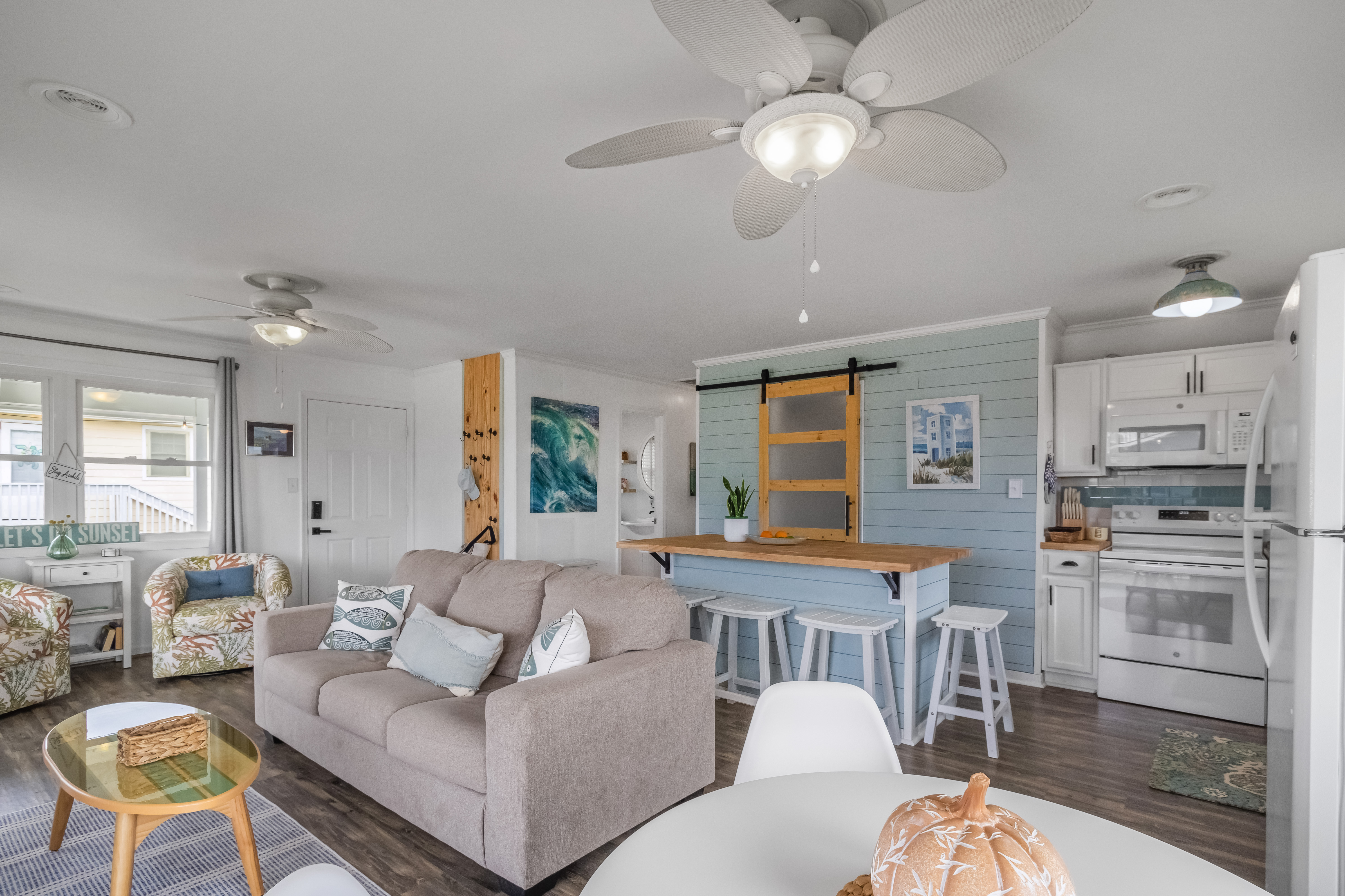 Bright coastal open-concept living space with breakfast bar and full kitchen