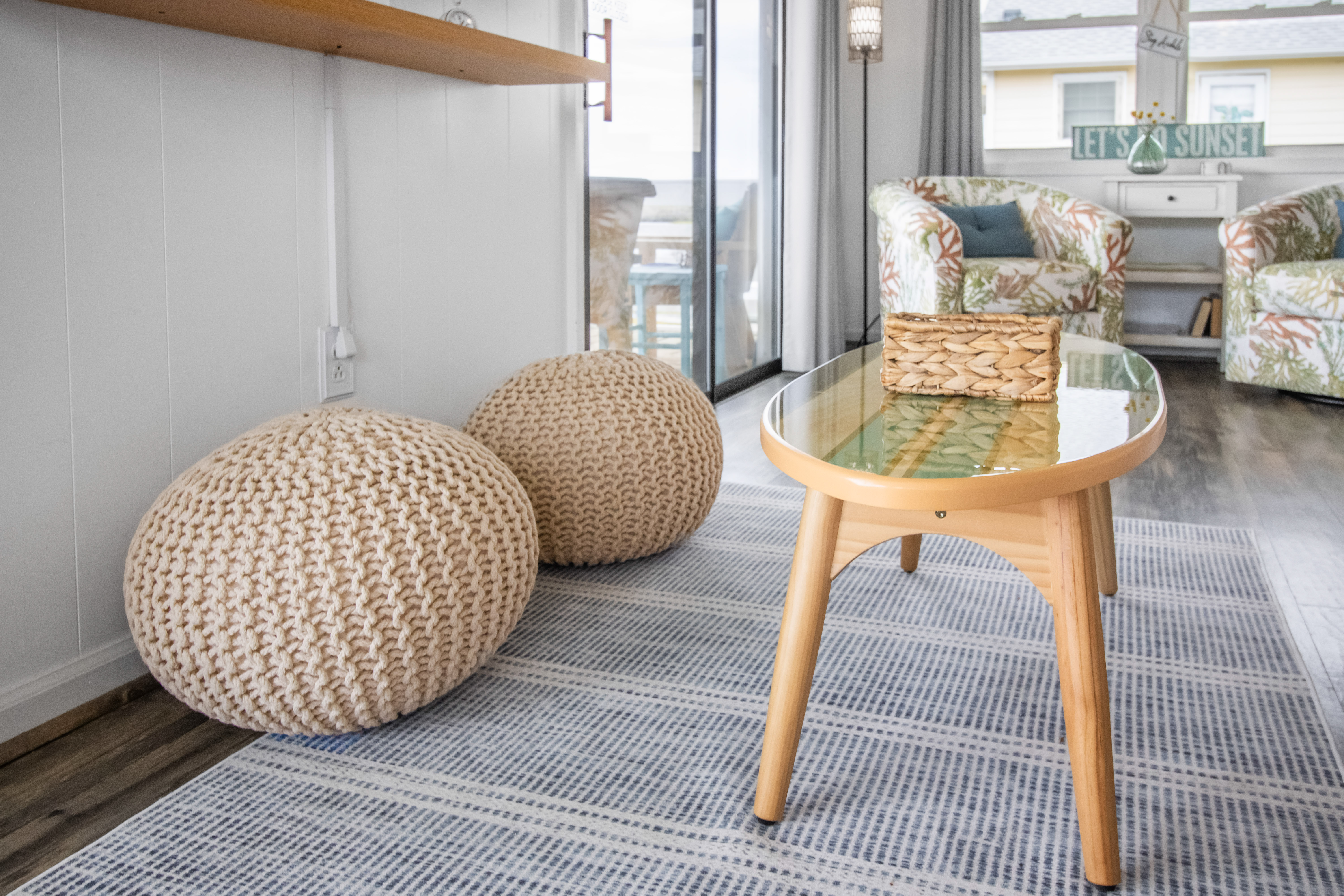 Bright coastal lounge with knit poufs, sunny seating, and balcony access