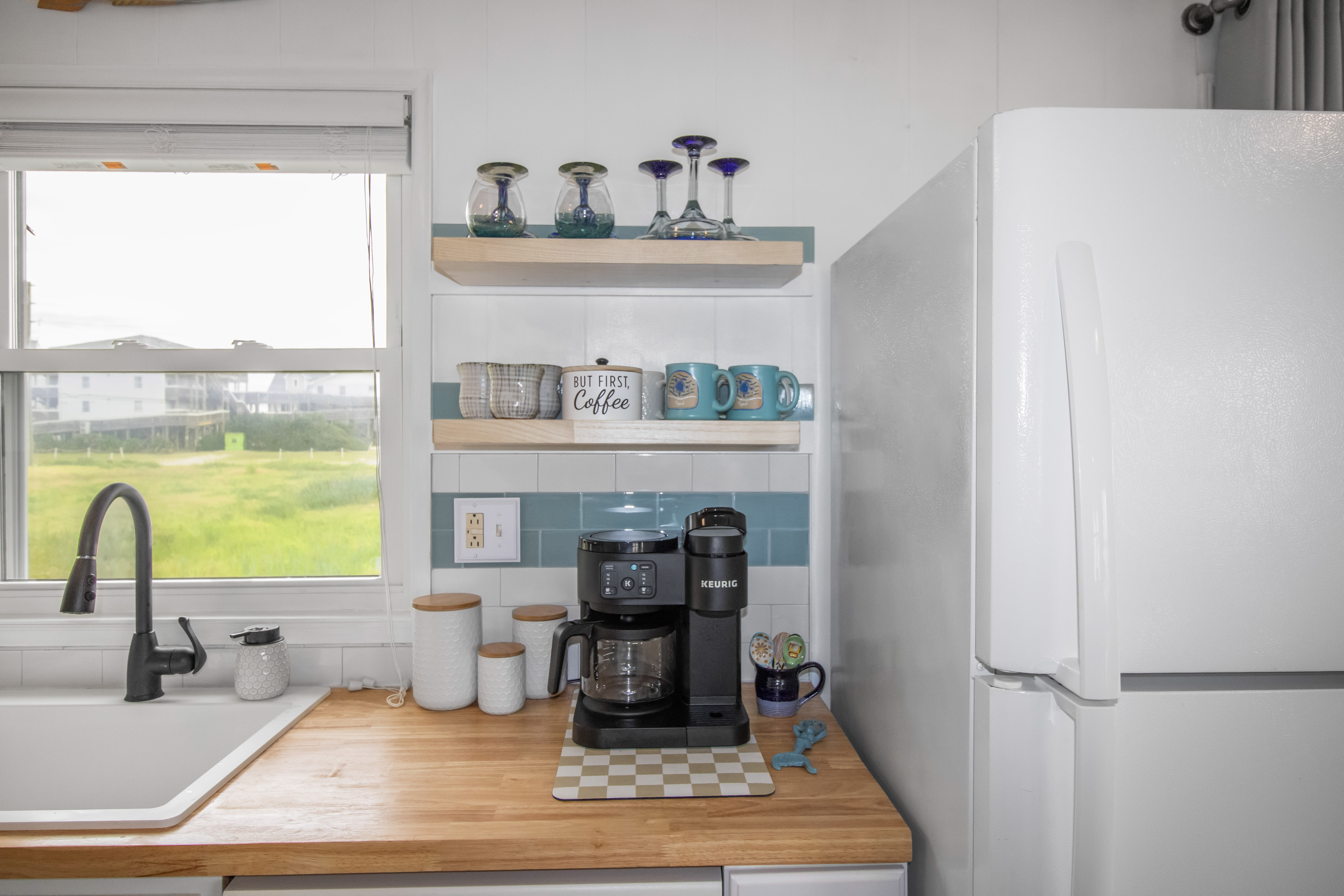 Bright kitchen with coffee station, open shelving, and sunny window views