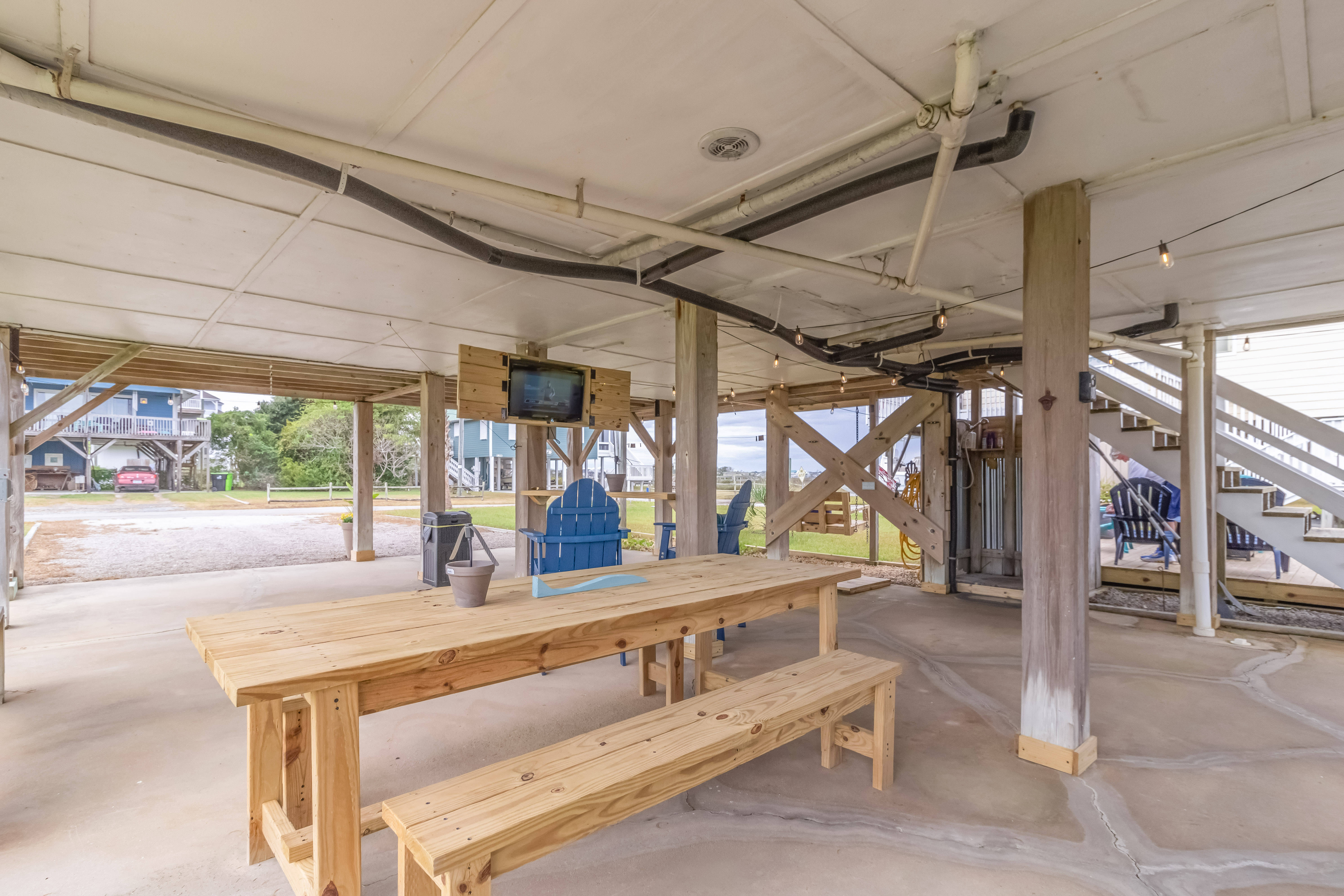 Covered outdoor hangout with picnic table, TV, and relaxed beach-house vibes