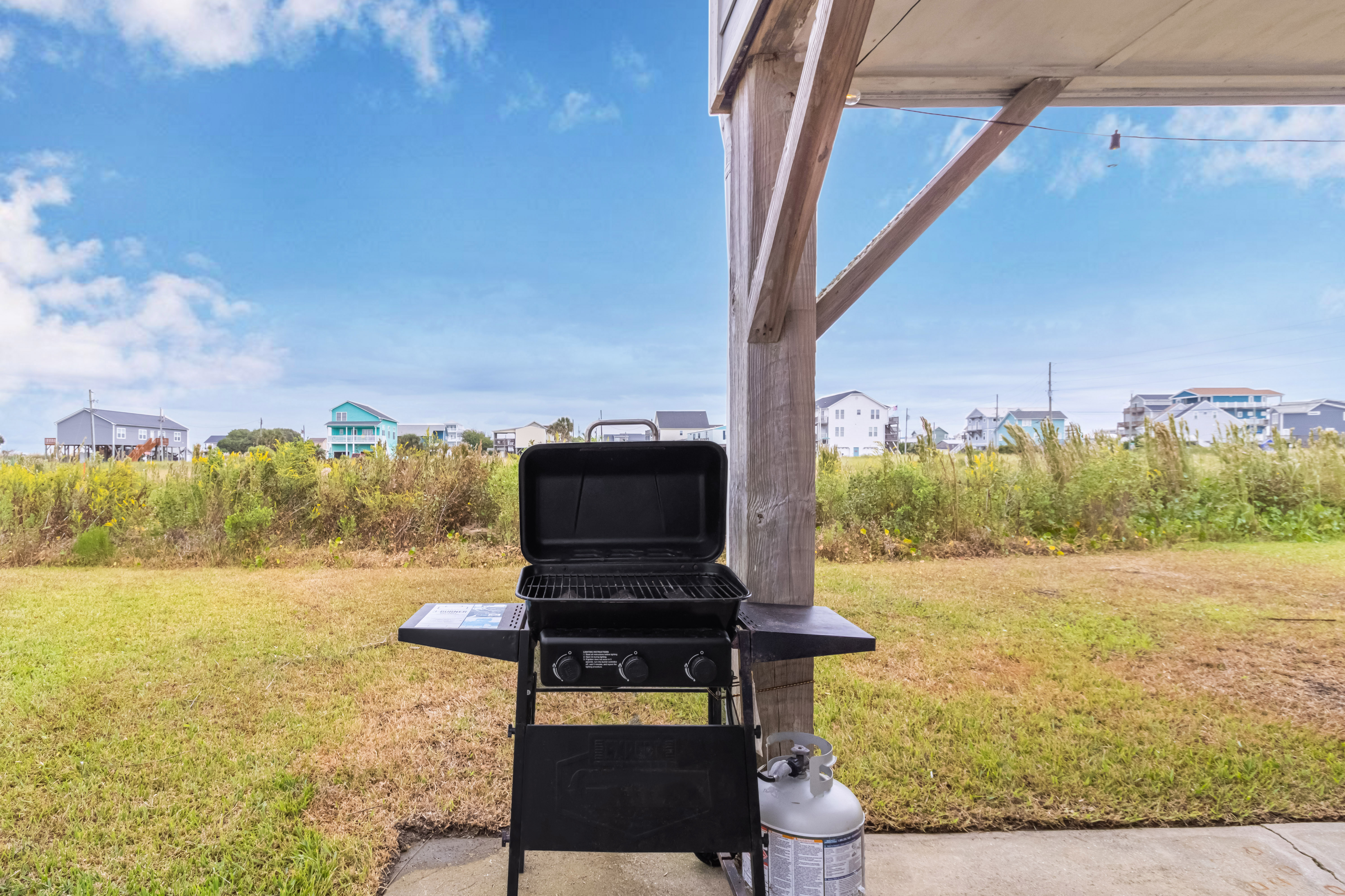 Covered patio with gas grill and open coastal backyard views