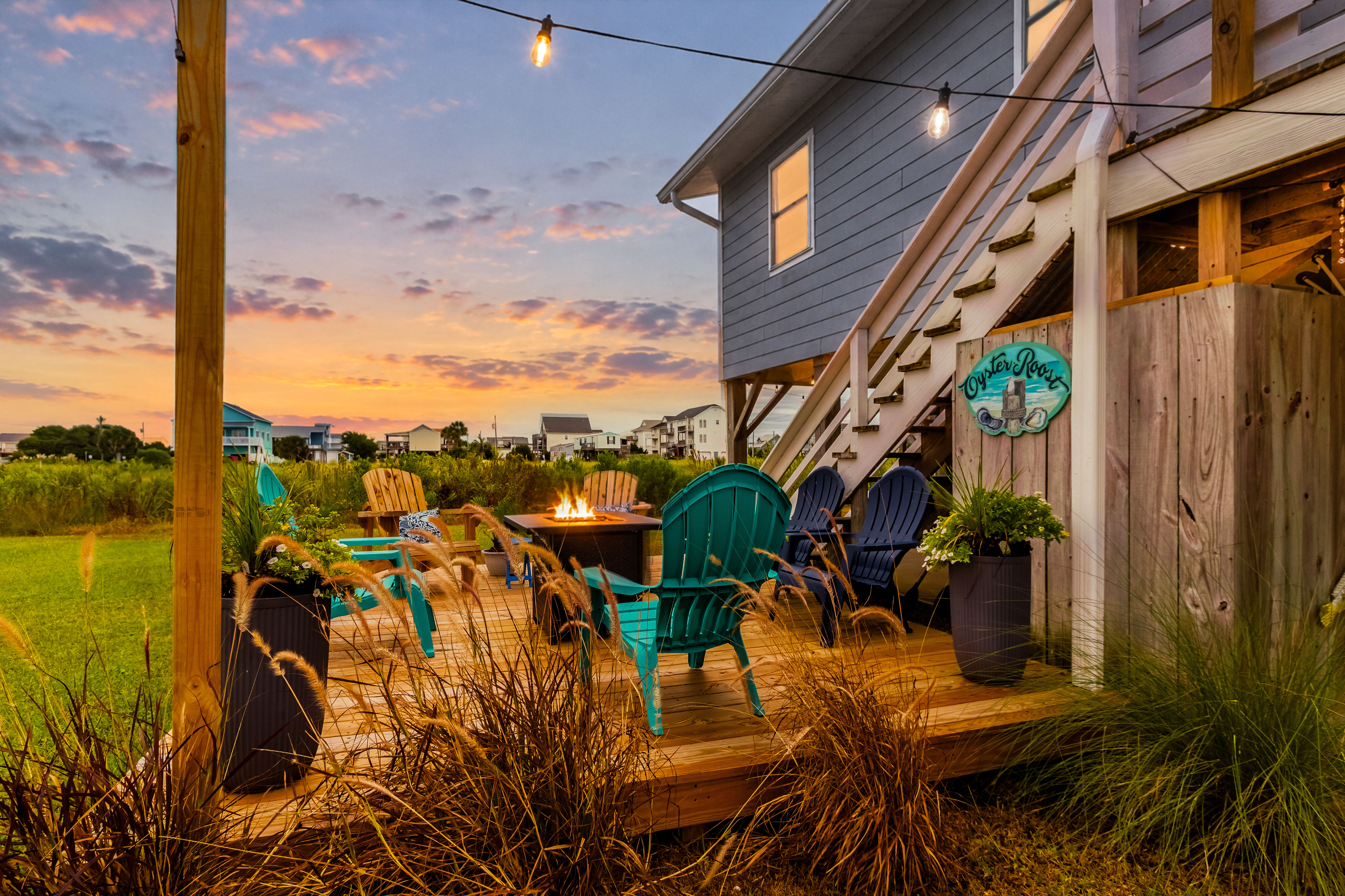 Sunset deck with fire pit, string lights, and cozy coastal seating