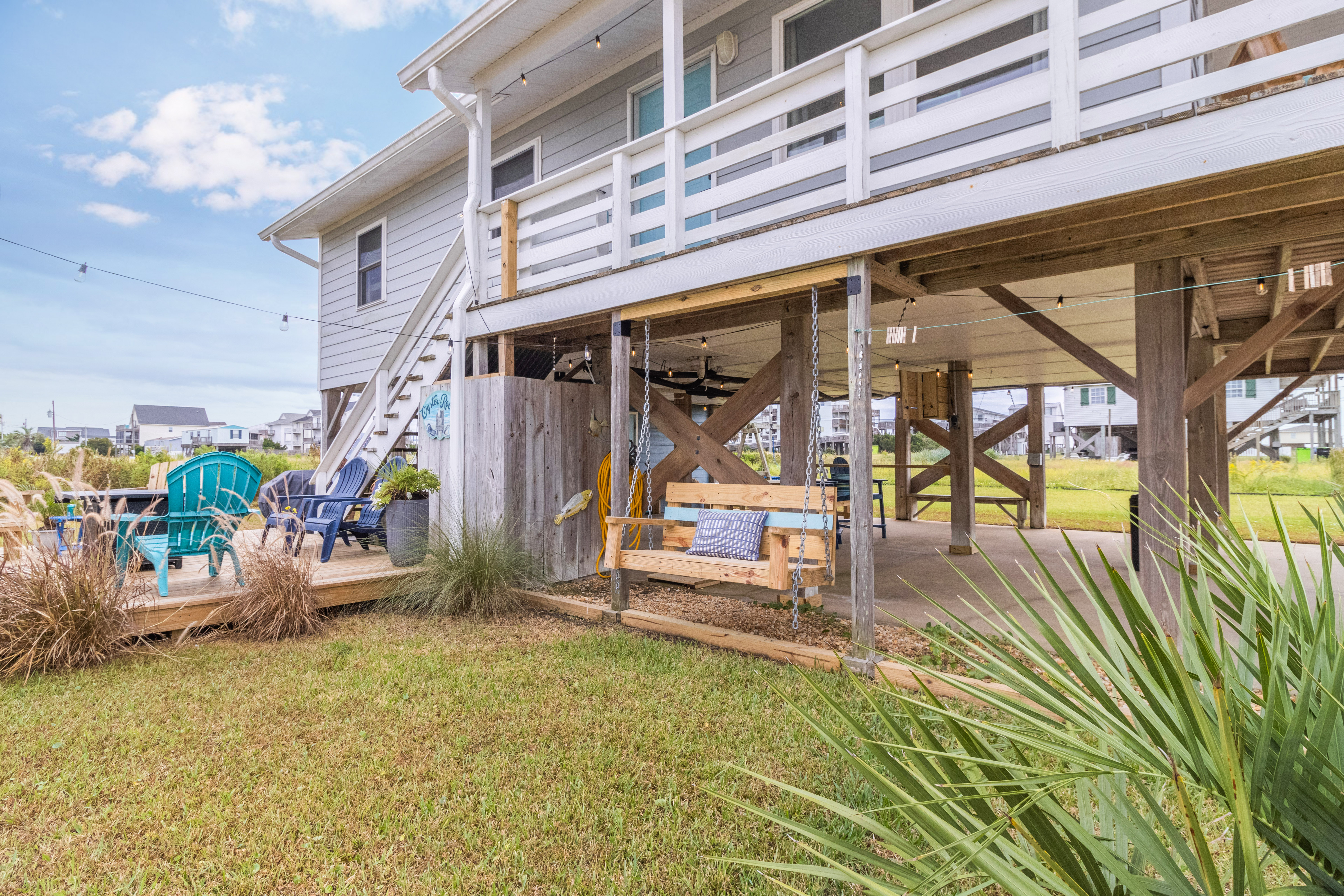 Relax under the beach house with a porch swing, deck seating, and open yard