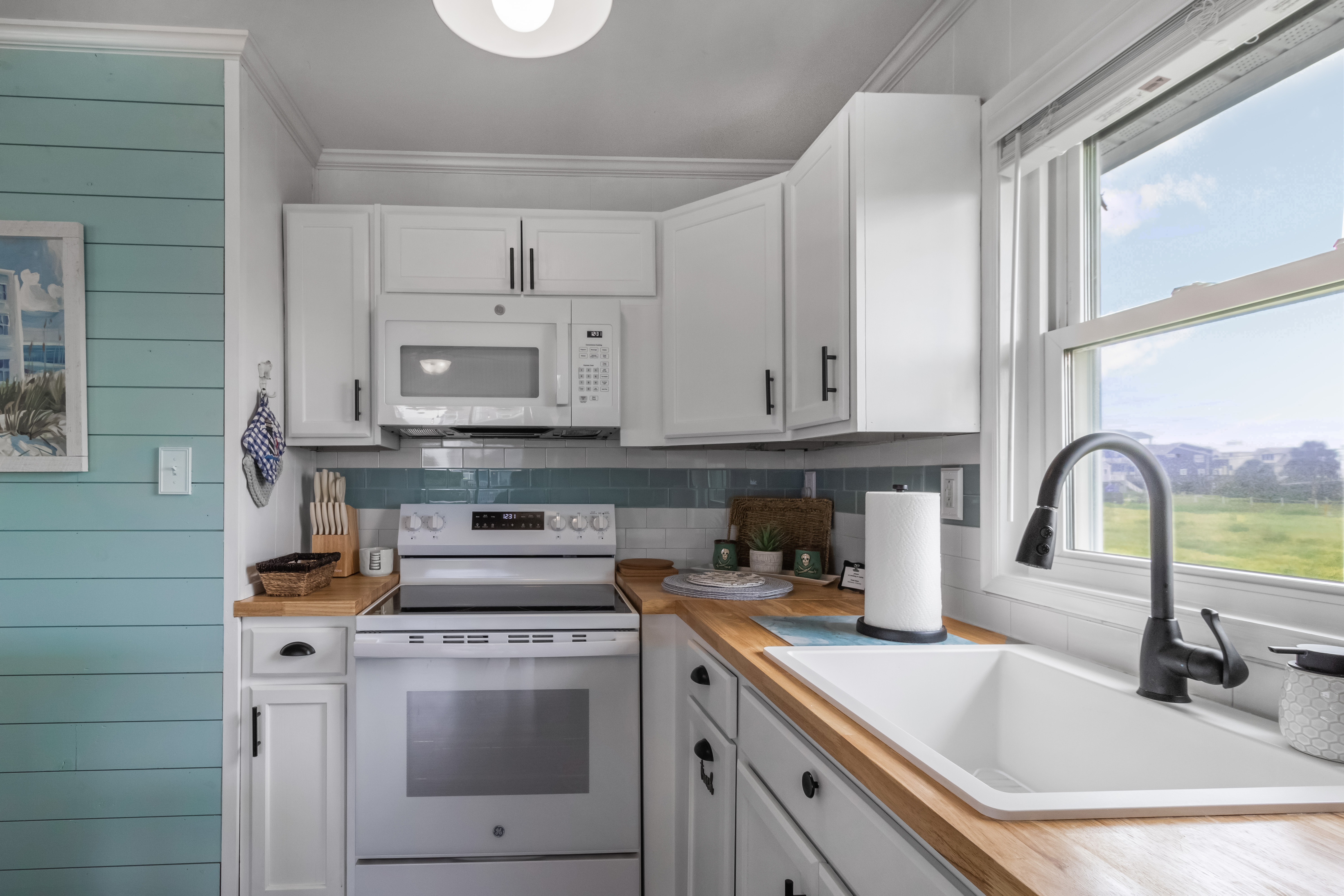 Bright coastal kitchen with farmhouse sink and sunny outdoor views