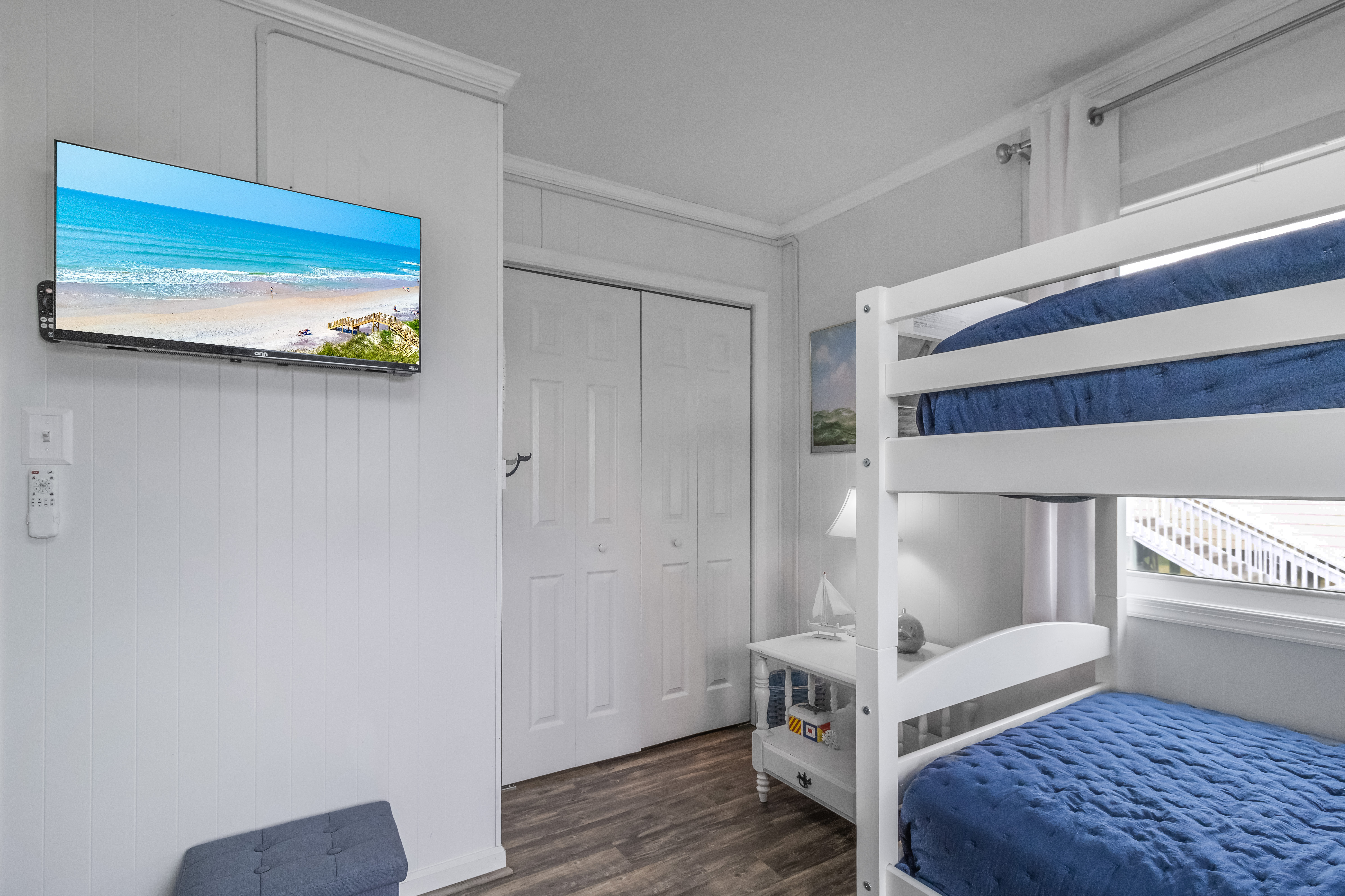 Bright bunk room with TV, closet, and cozy coastal style