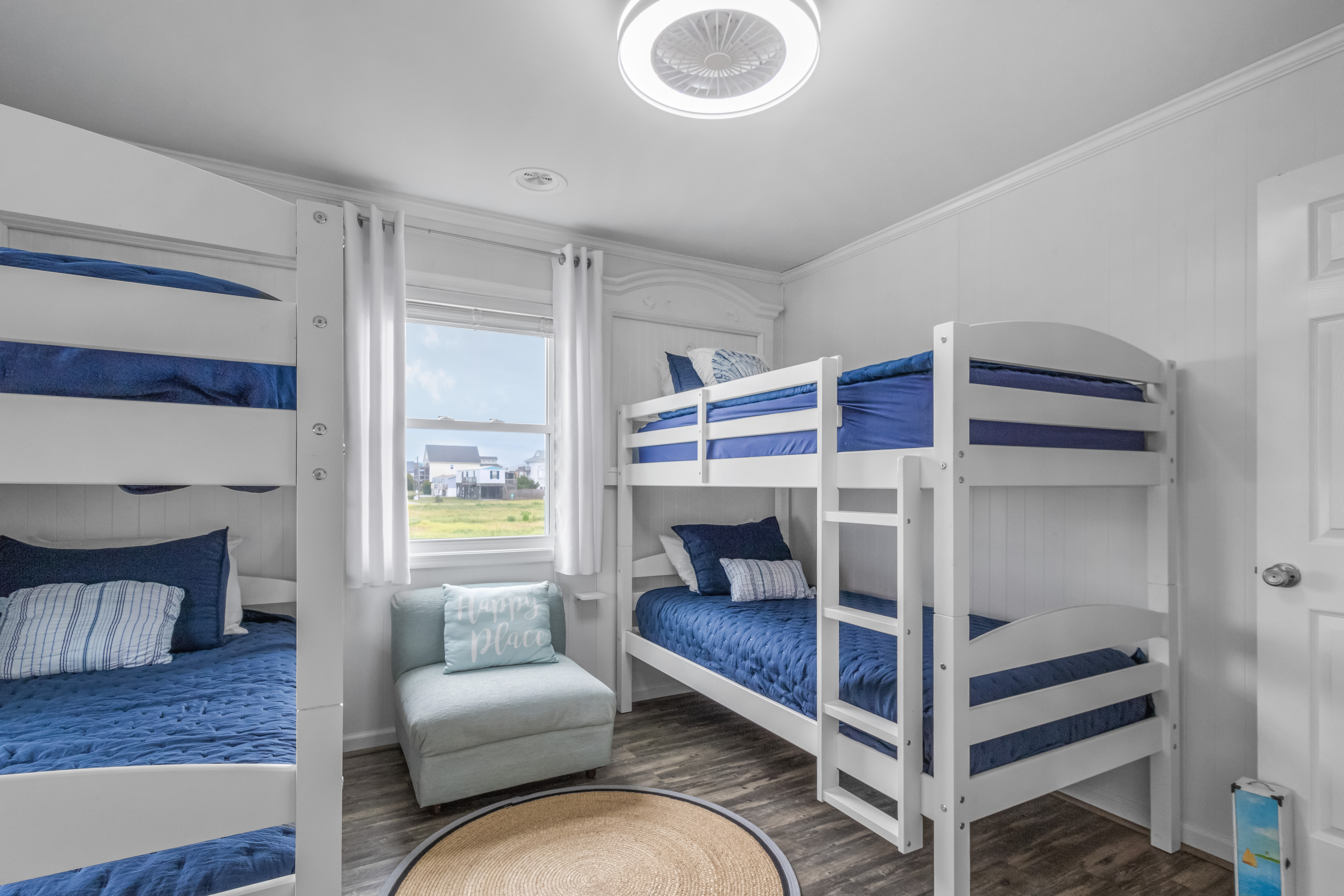 Bright bunk room with four beds, natural light, and coastal-inspired style