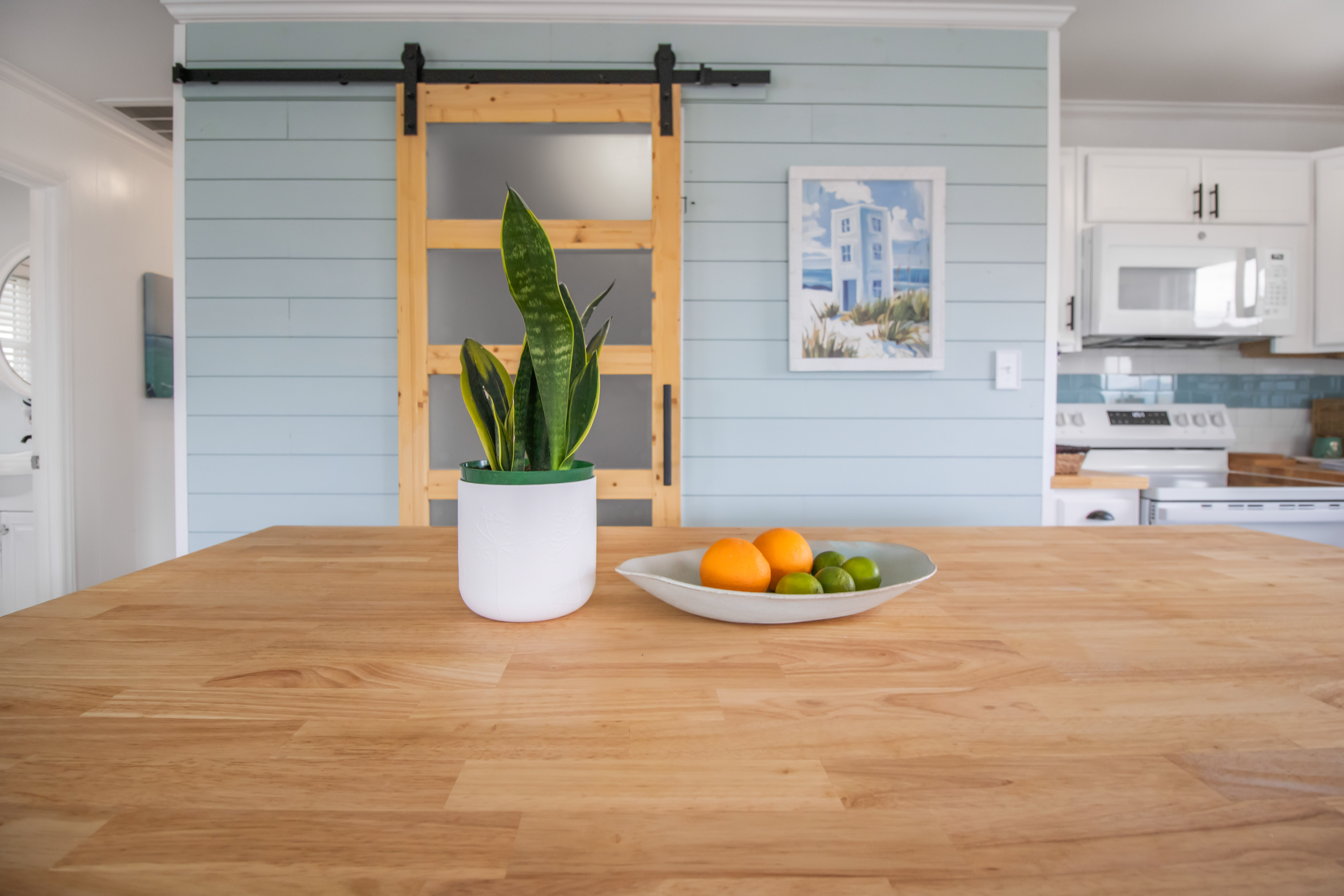 Bright coastal kitchen with butcher-block island and charming barn door