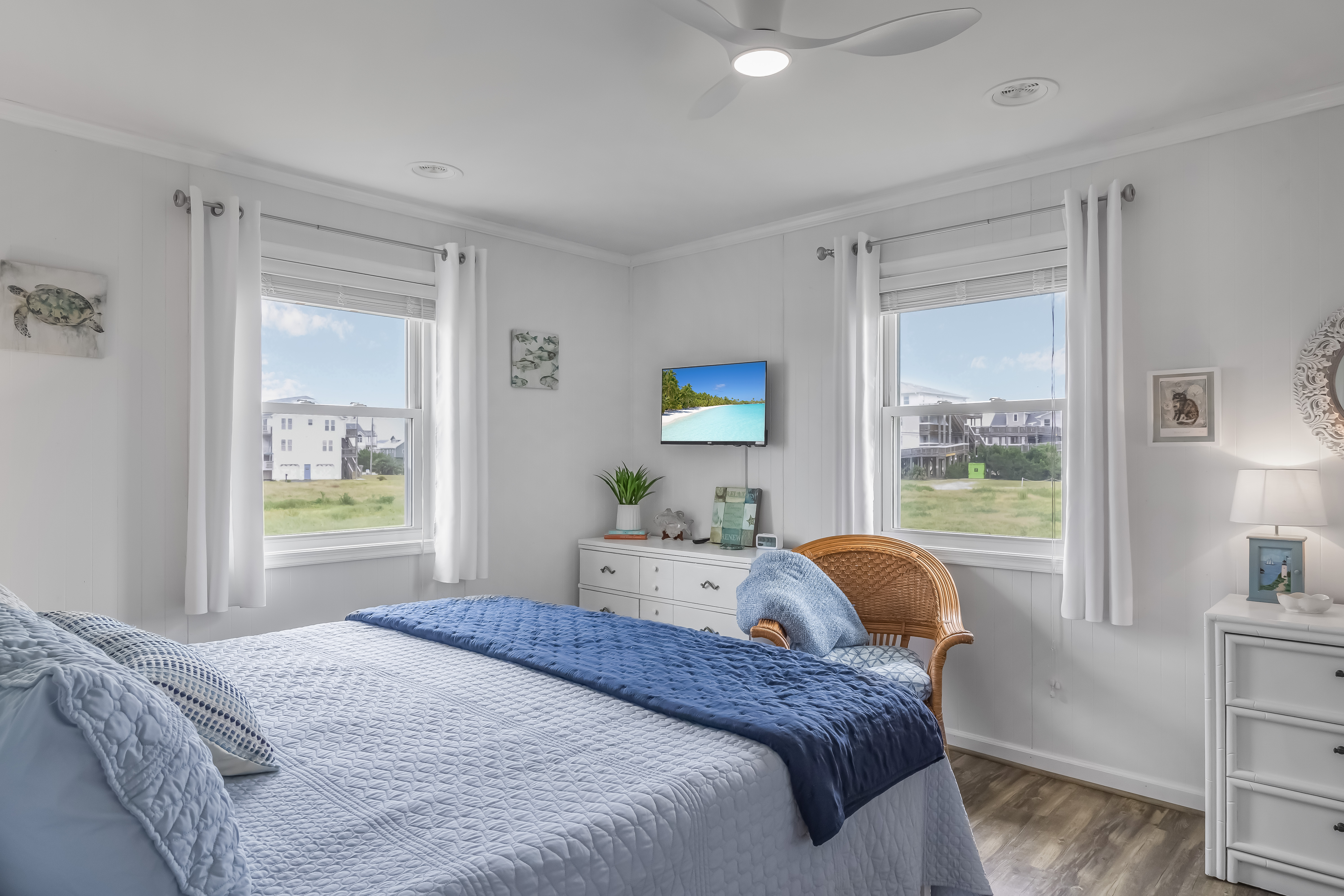 Bright coastal bedroom with TV, natural light, and serene beachy style