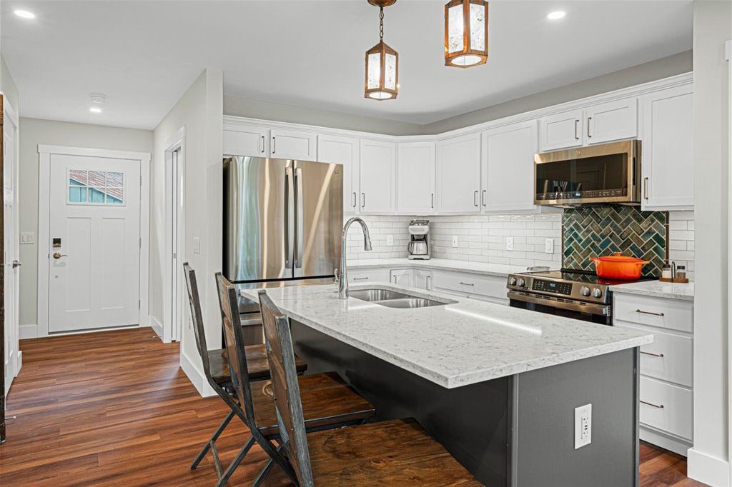 The bright kitchen features GE Profile appliances, a coffee station, handmade raku tiles in the backsplash, and custom copper and mica lighting