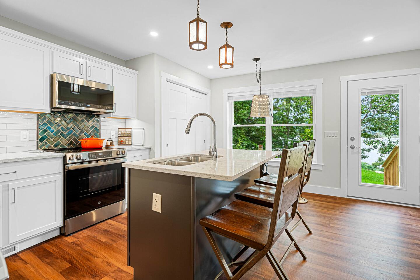 The kitchen features additional seating (3 chairs at the island and a bistro table on the far side), handmade raku tiles, GE Profile appliances, and high-end small appliances.
