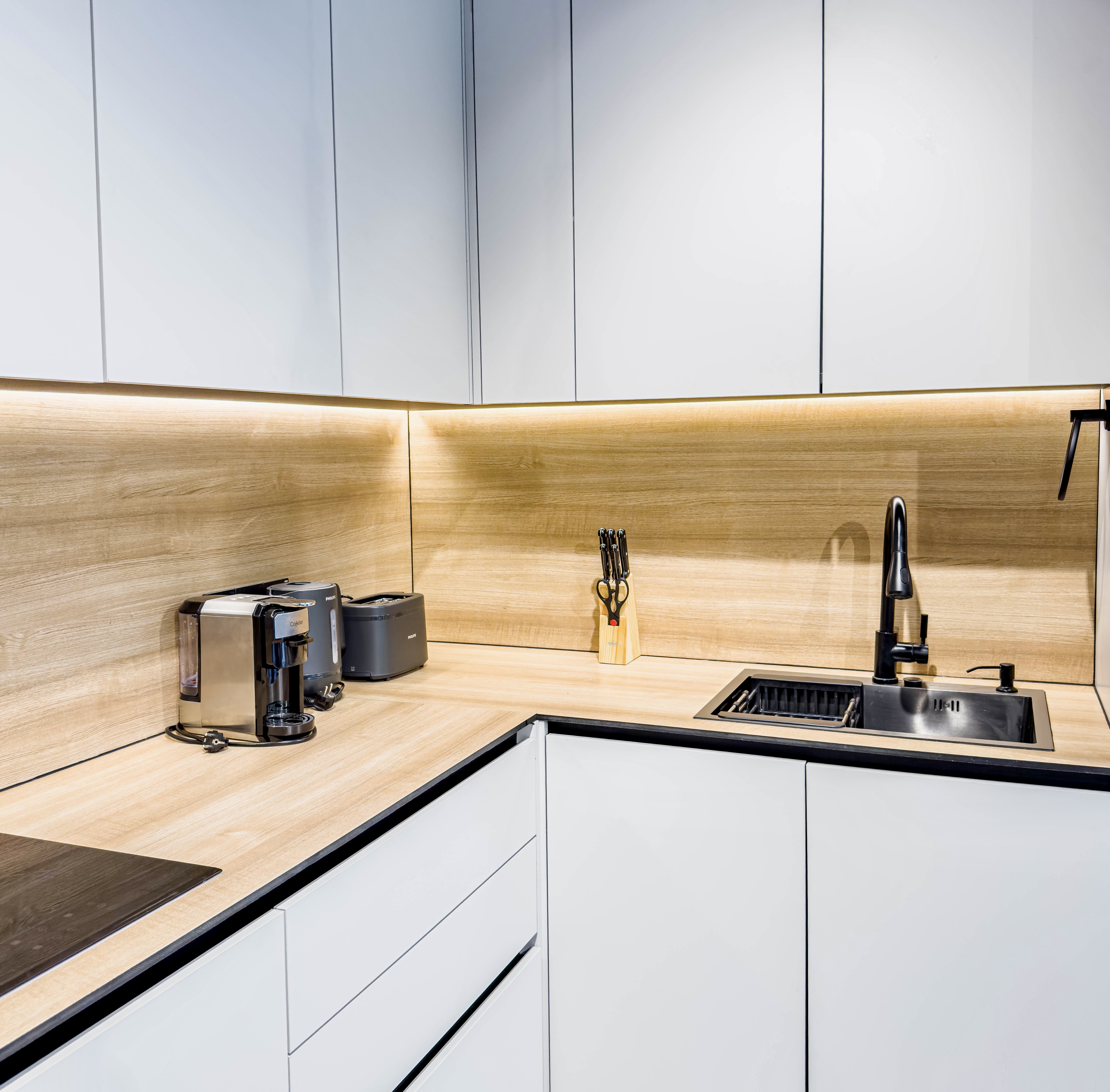 Modern kitchenette with warm lighting, coffee station, and sleek finishes