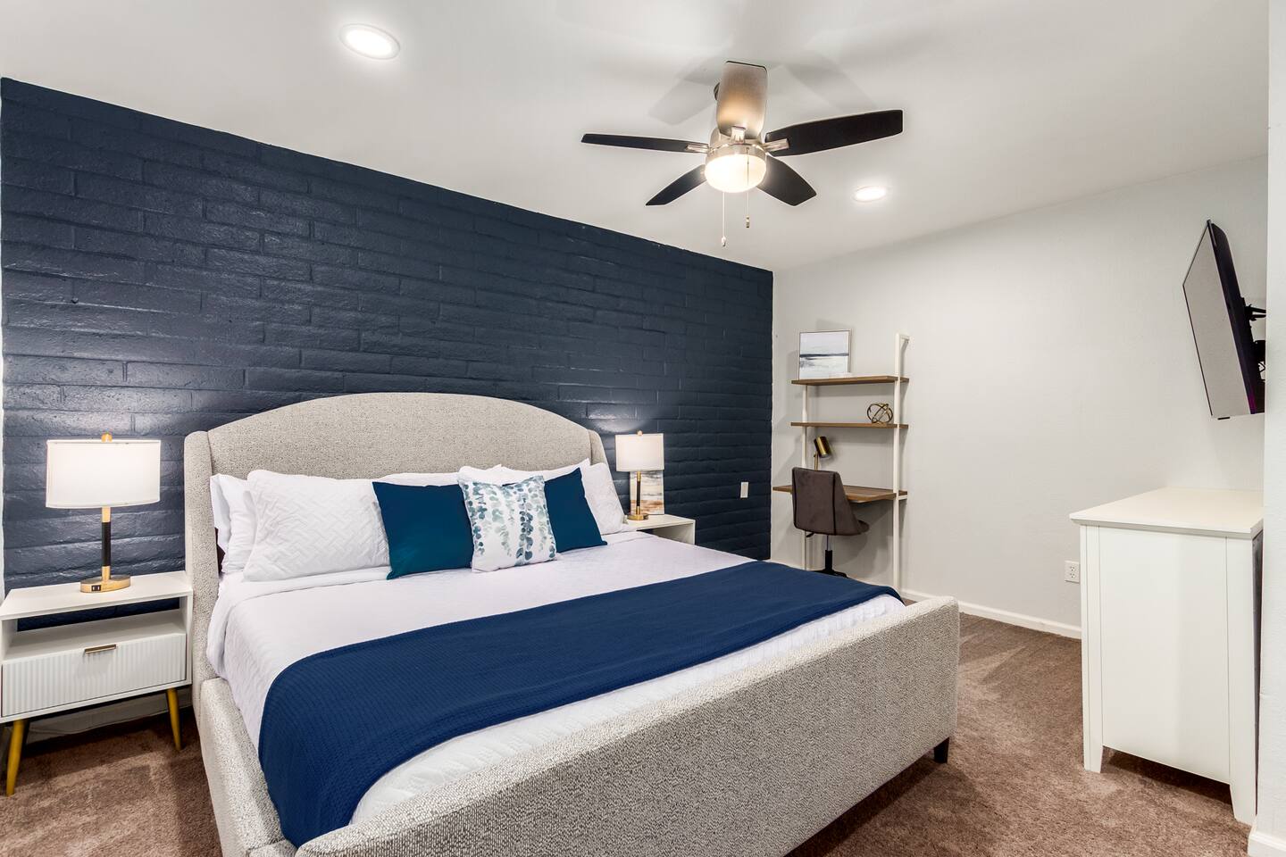 Retreat to the guest house bedroom featuring a plush king bed,  desk, dresser, and 55" TV—your own private haven designed for comfort, relaxation, and a peaceful night’s rest.