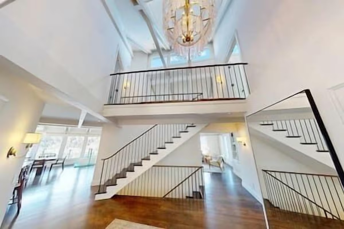 Grand entryway with soaring ceilings, chandelier, and elegant staircase