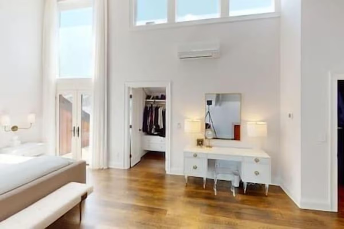 Spacious high-ceiling bedroom with vanity, walk-in closet, and natural light