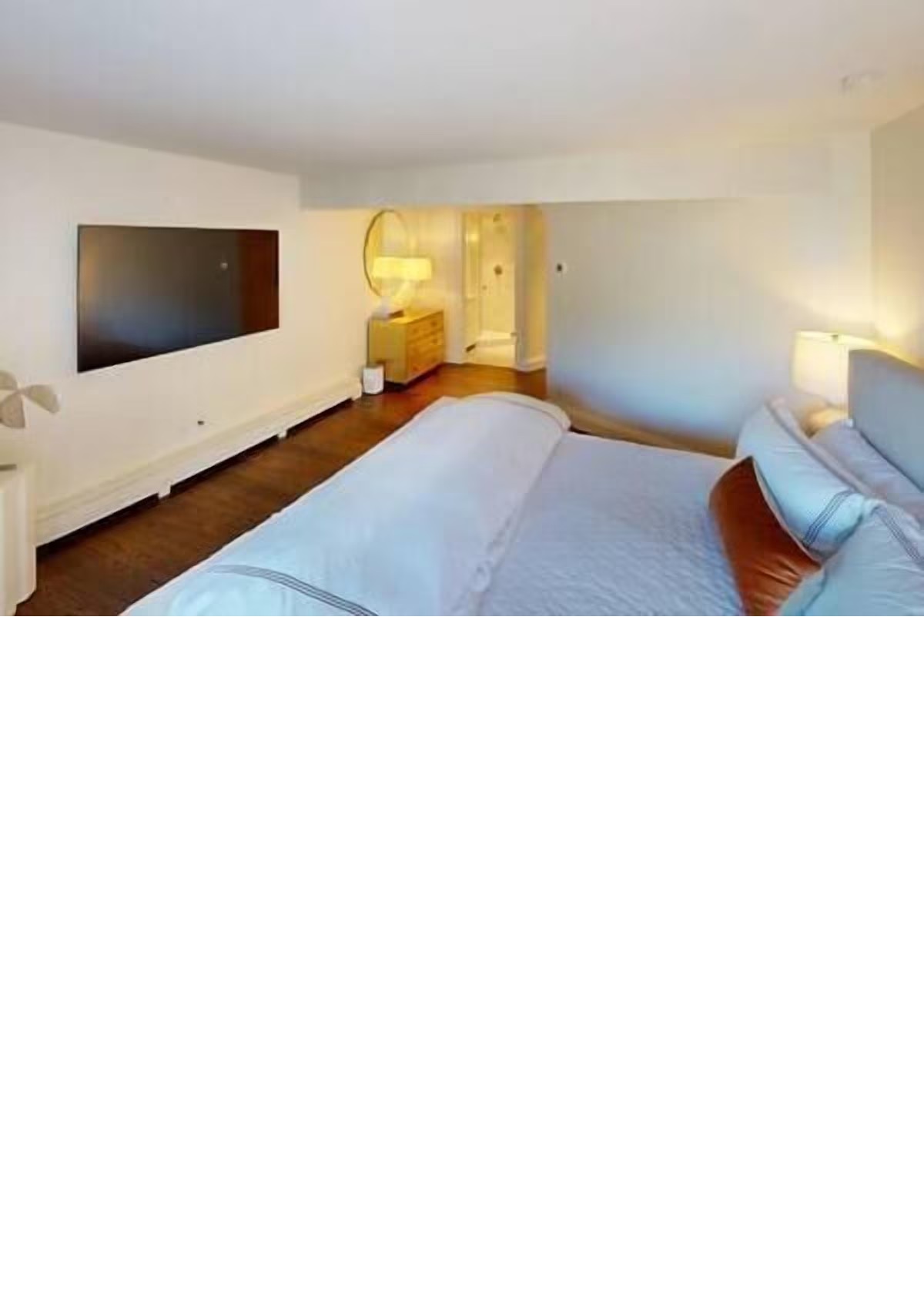 Spacious king bedroom with TV, warm lighting, and ensuite vanity area
