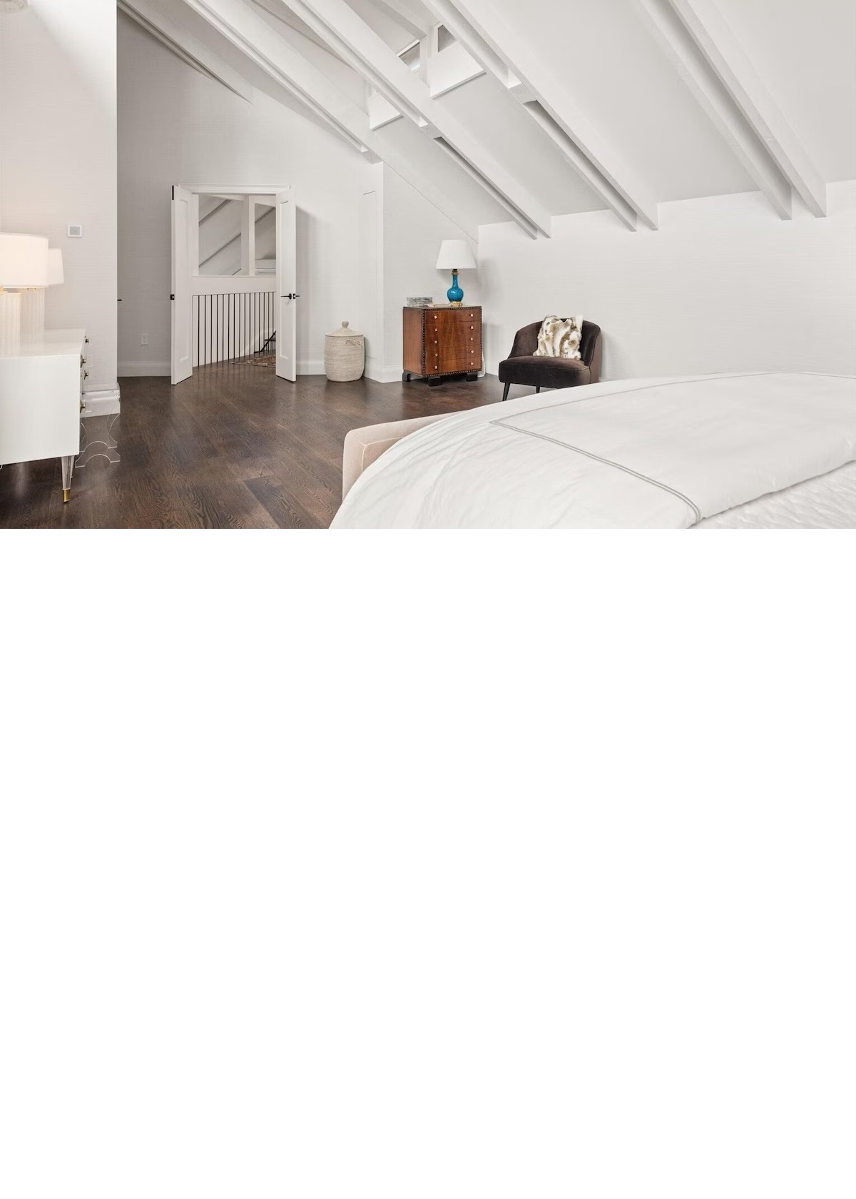 Bright vaulted bedroom with exposed beams and cozy lounge corner