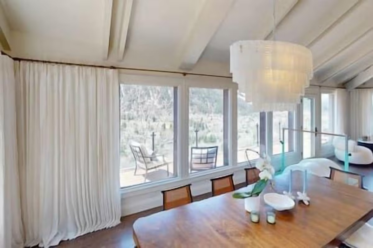 Bright window-lined dining room with stylish chandelier and serene views