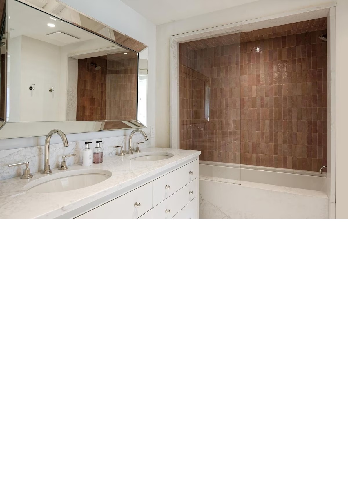 Bright double-vanity bathroom with marble counters and tiled tub/shower