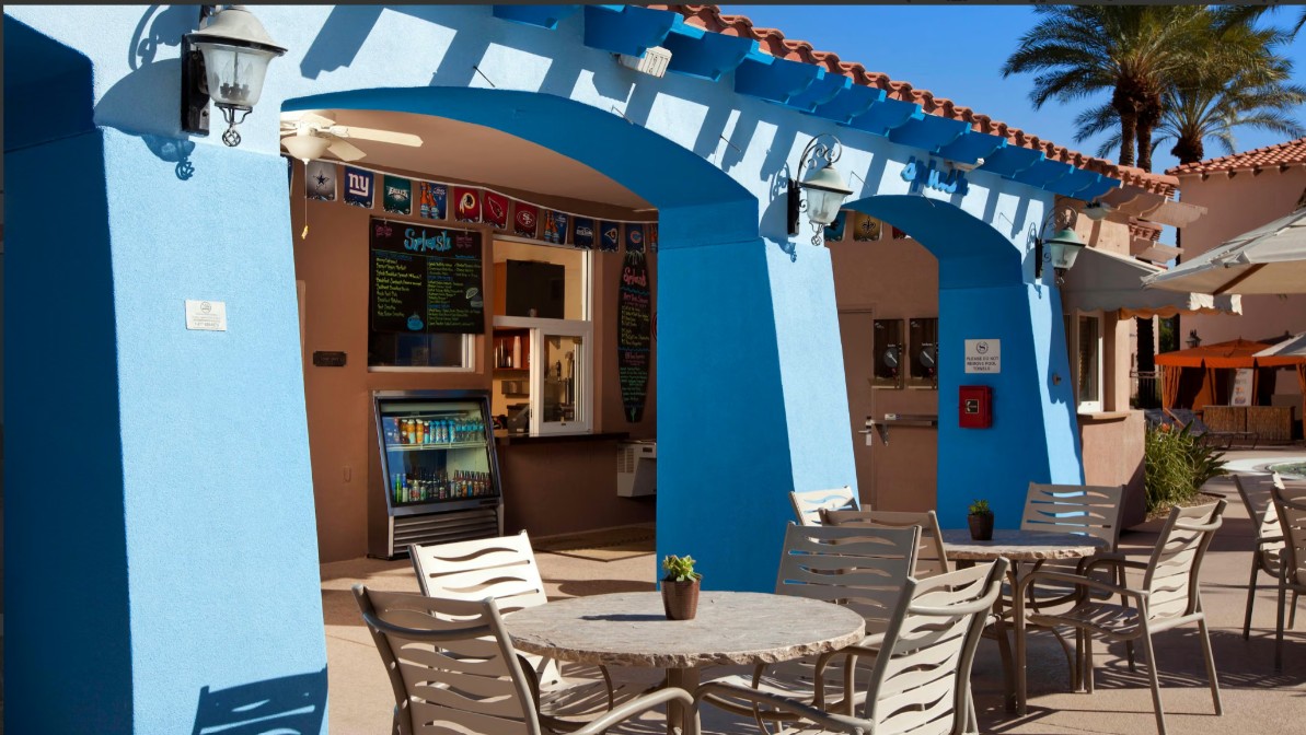 Sunny patio seating with vibrant blue arches and resort-style charm