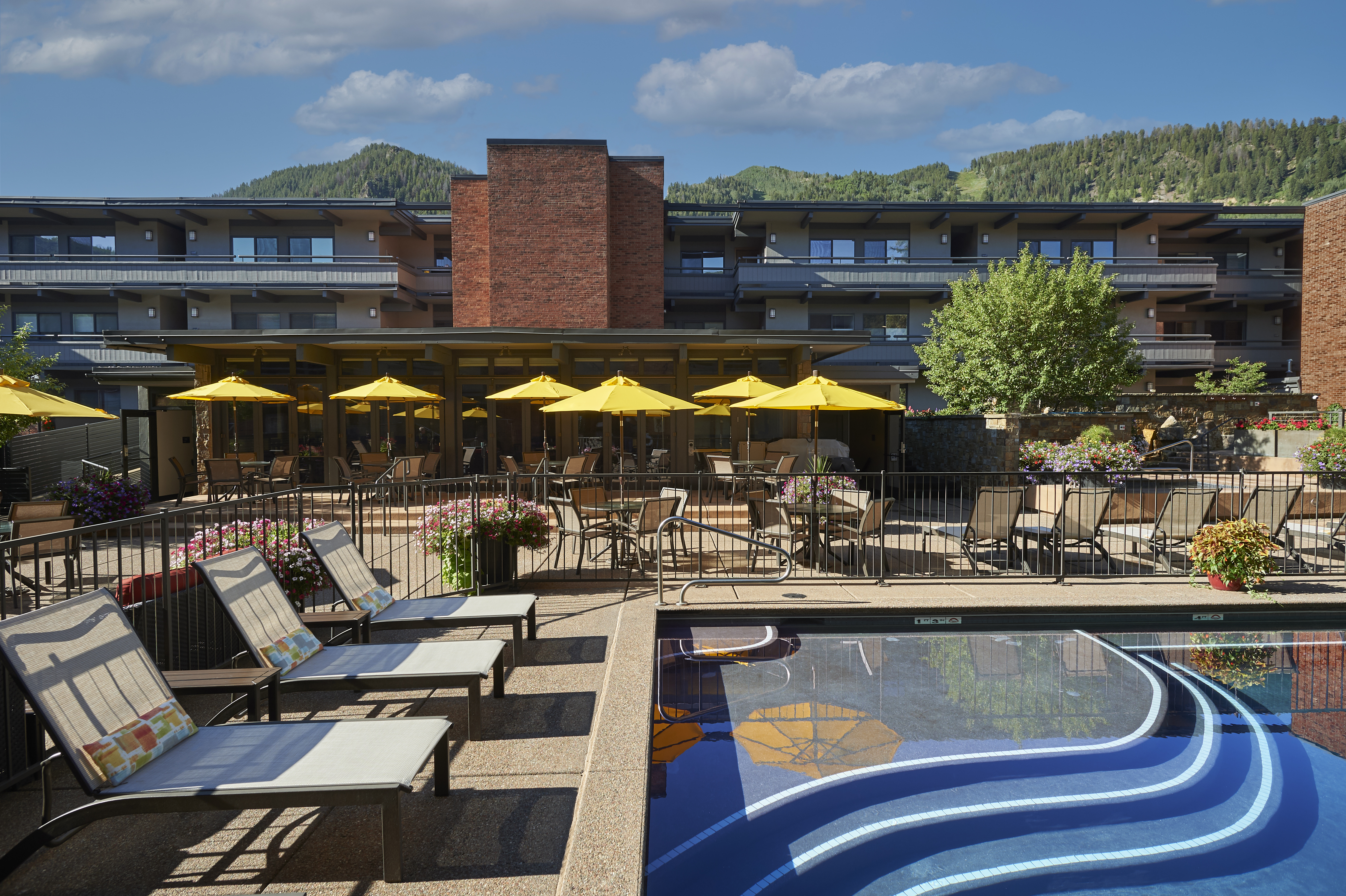 Resort-style pool deck with loungers, umbrellas, and mountain views