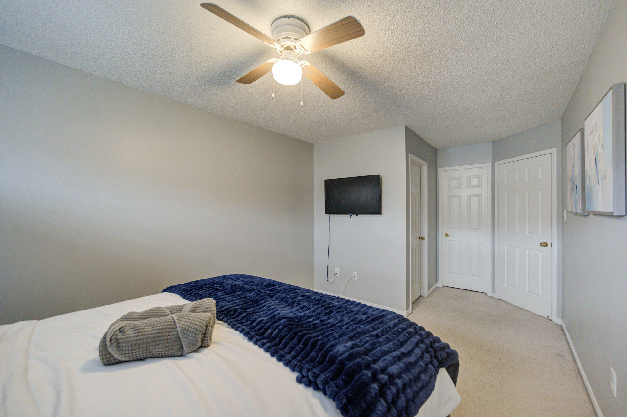 Cozy bedroom with TV, ceiling fan, and clean modern style