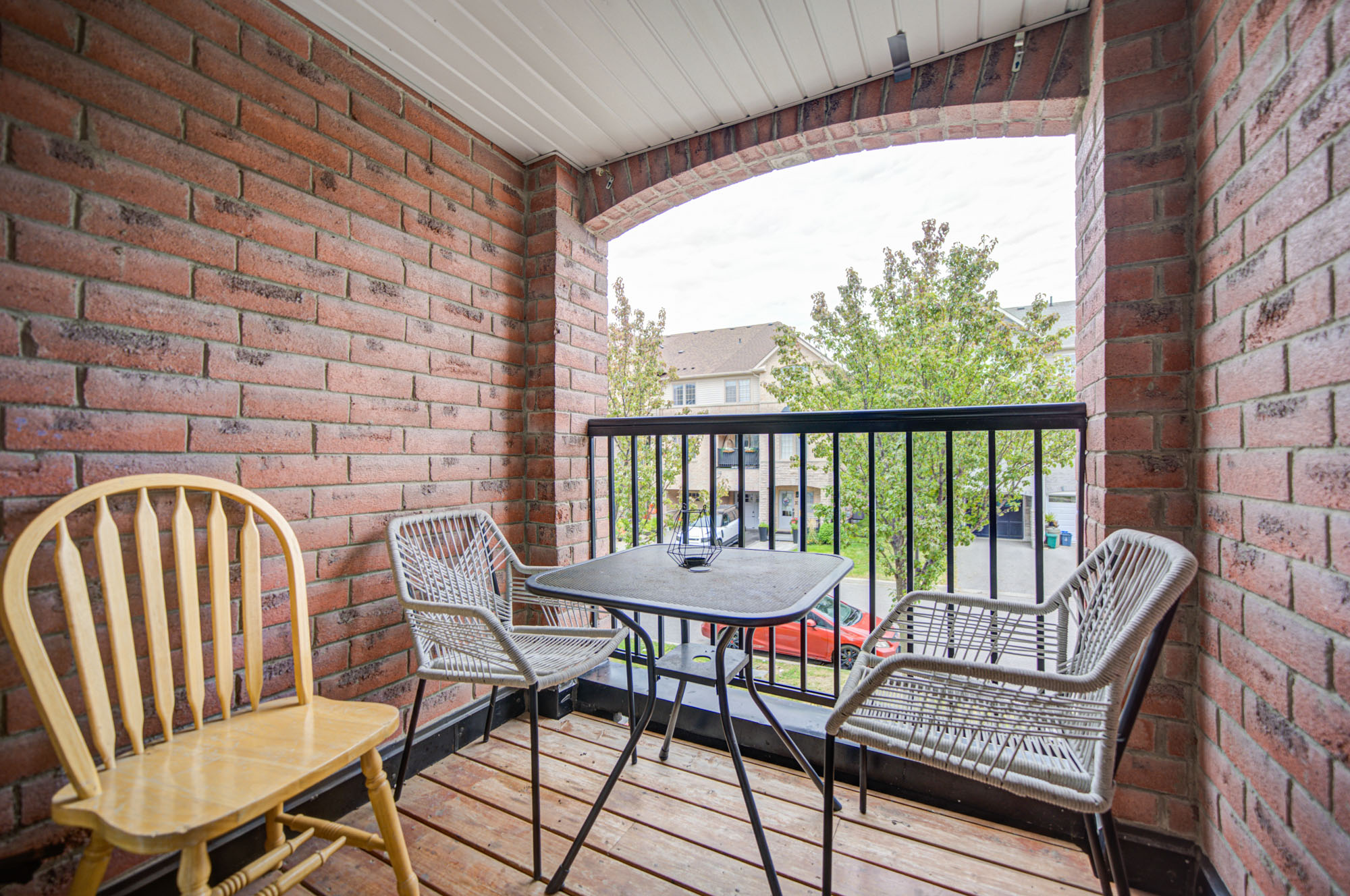 Charming covered brick balcony with cozy seating and leafy views