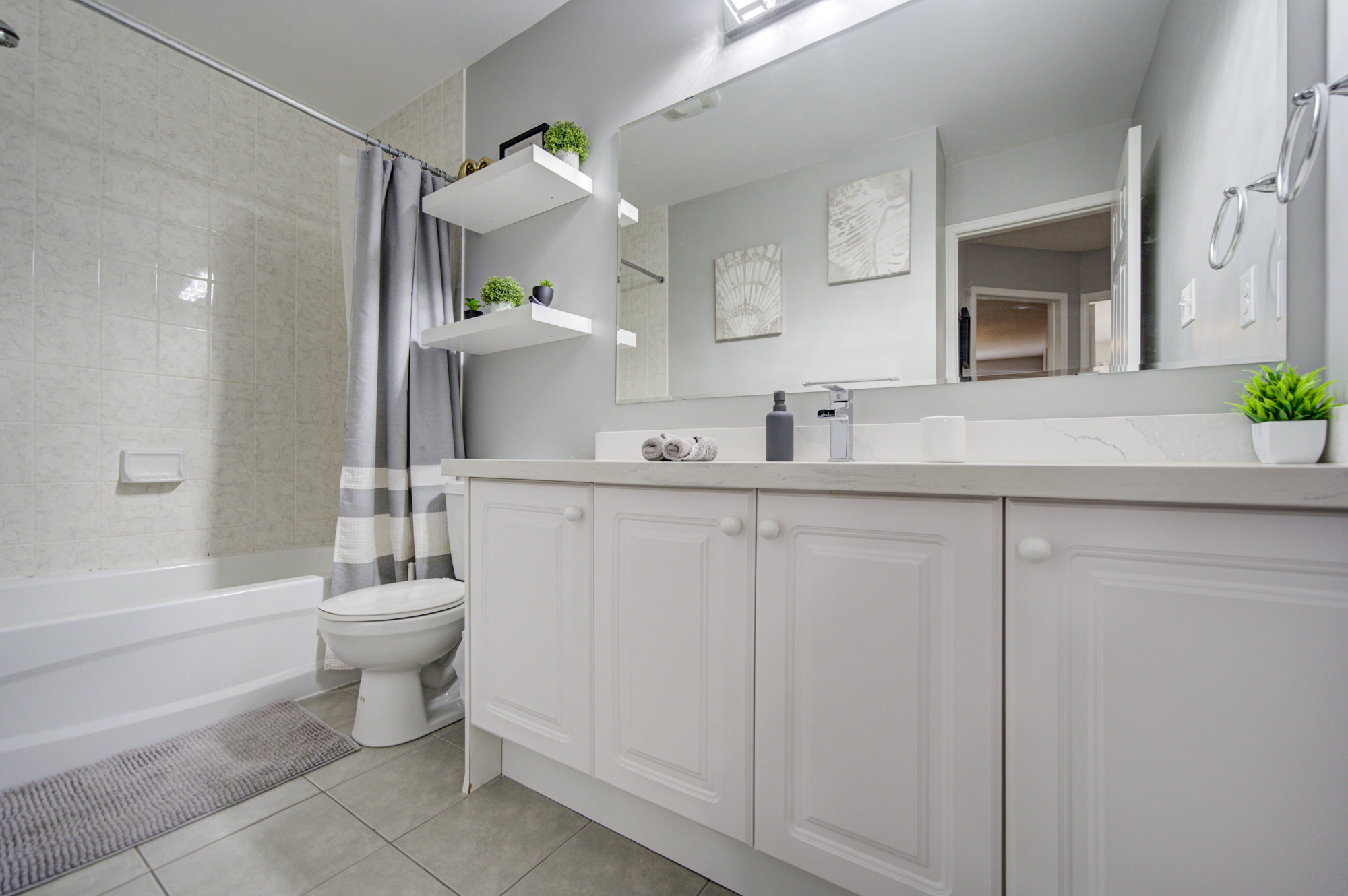 Bright modern bathroom with full tub, large vanity, and elegant finishes