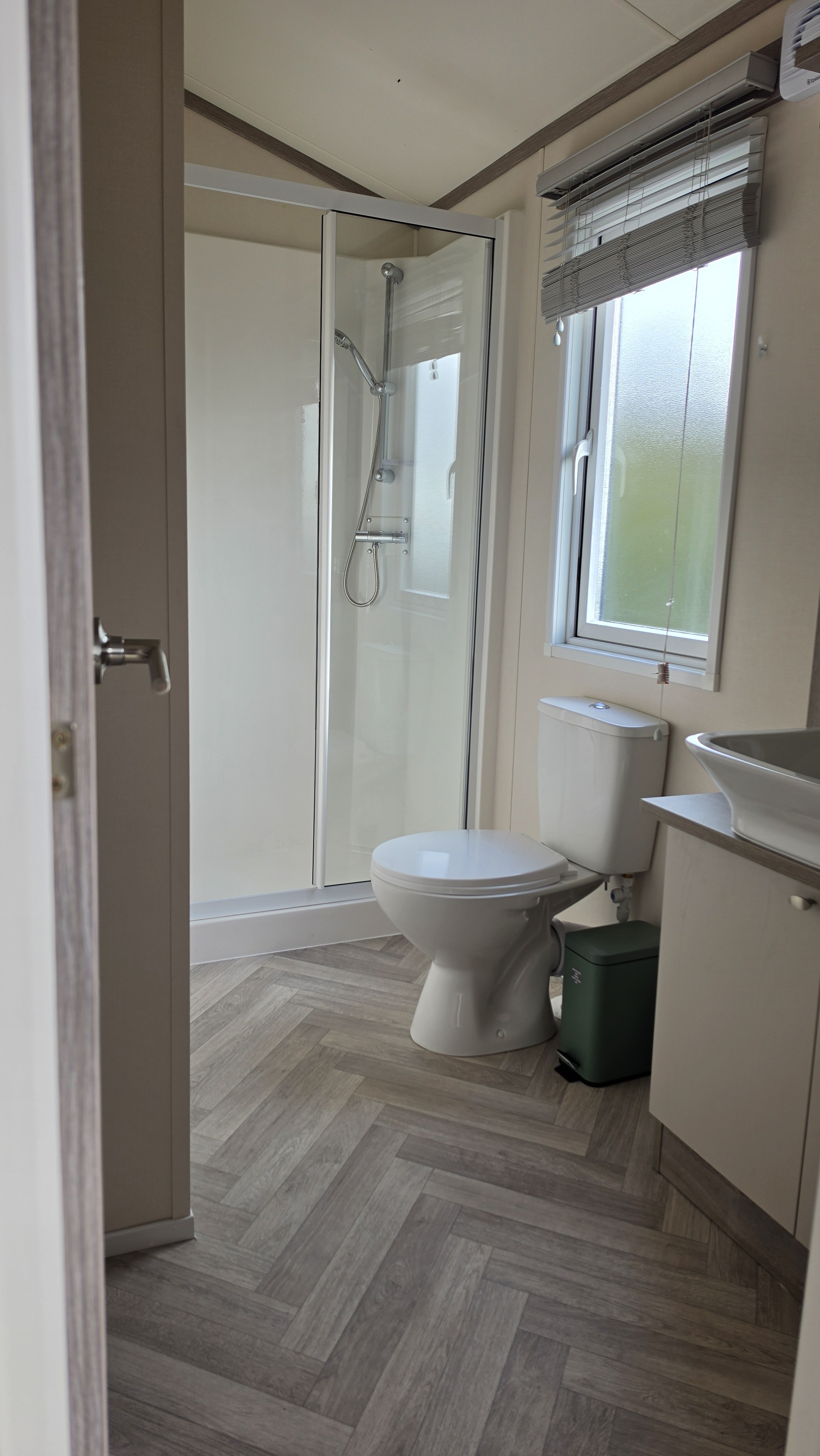 Bright modern bathroom with glass shower and stylish herringbone flooring