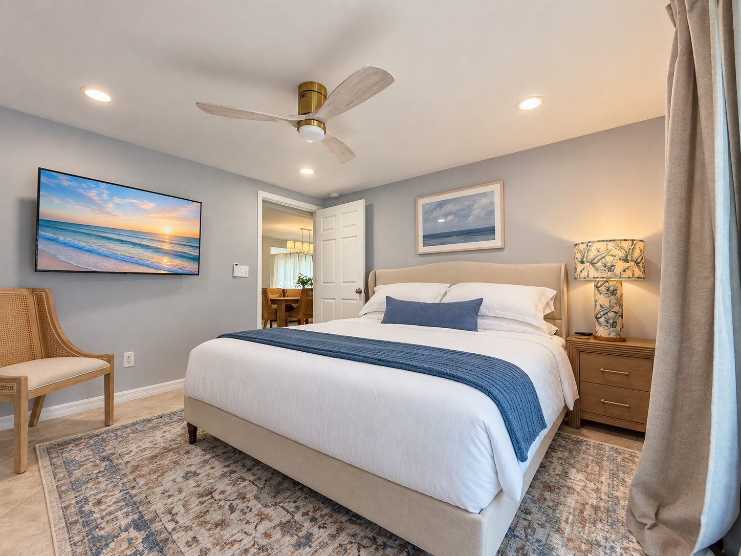 Coastal-inspired king bedroom with TV, soft lighting, and serene style