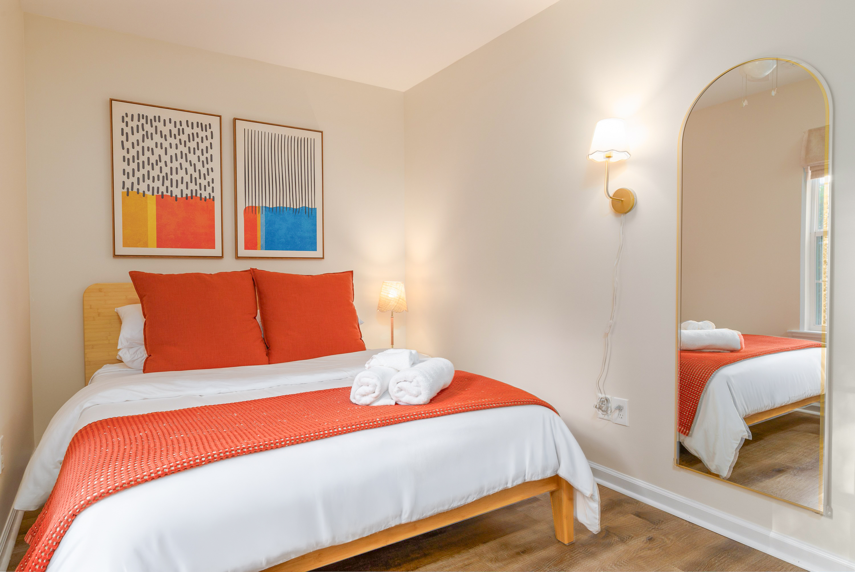 Bedroom 2: queen bed, arched full-length mirror and wall sconce
