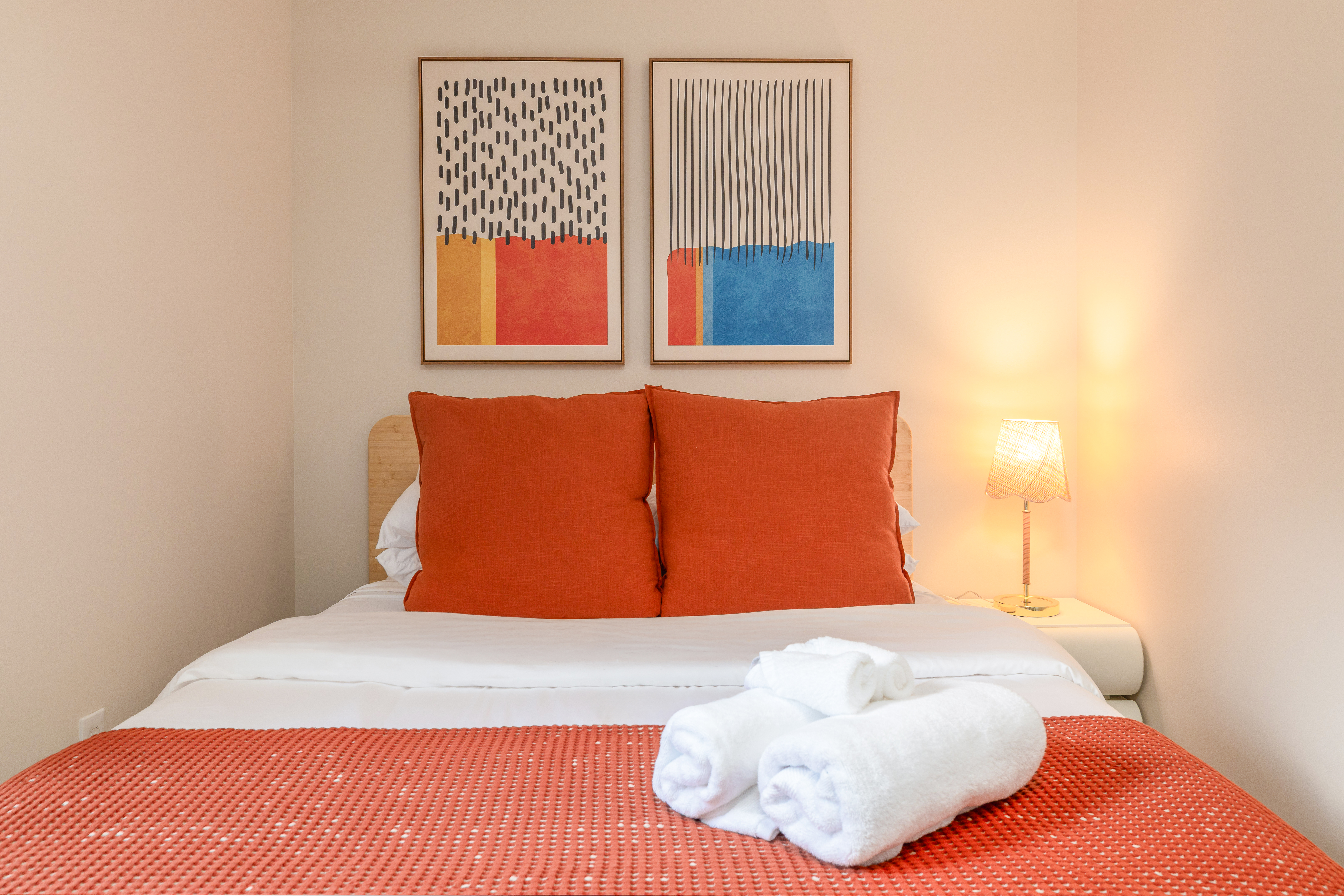 Bedroom 2: queen bed with fresh towels, under a pair of framed prints