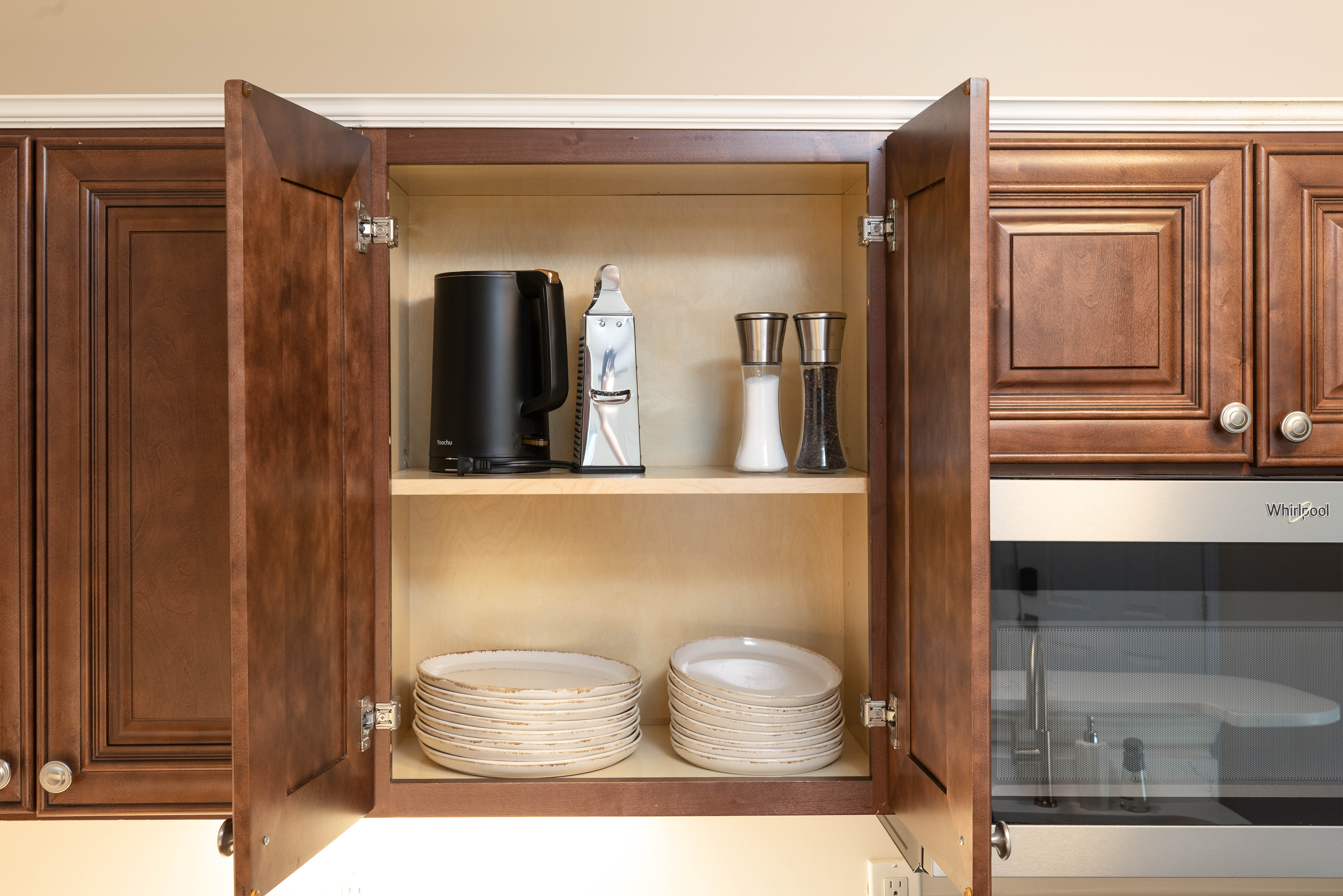 Cabinet with plates and an electric kettle, beside the microwave