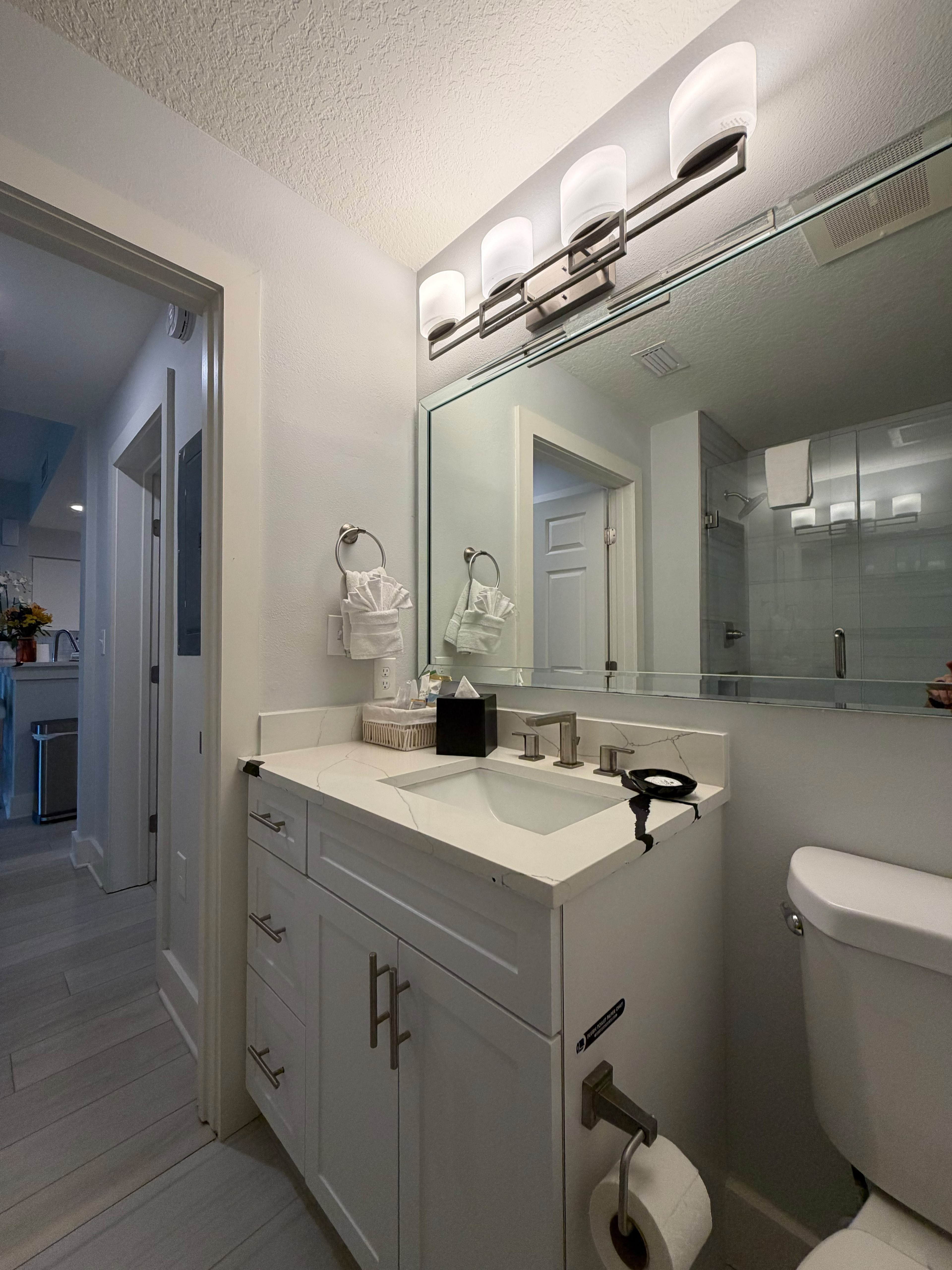 Bright modern bathroom with sleek vanity, large mirror, and glass shower