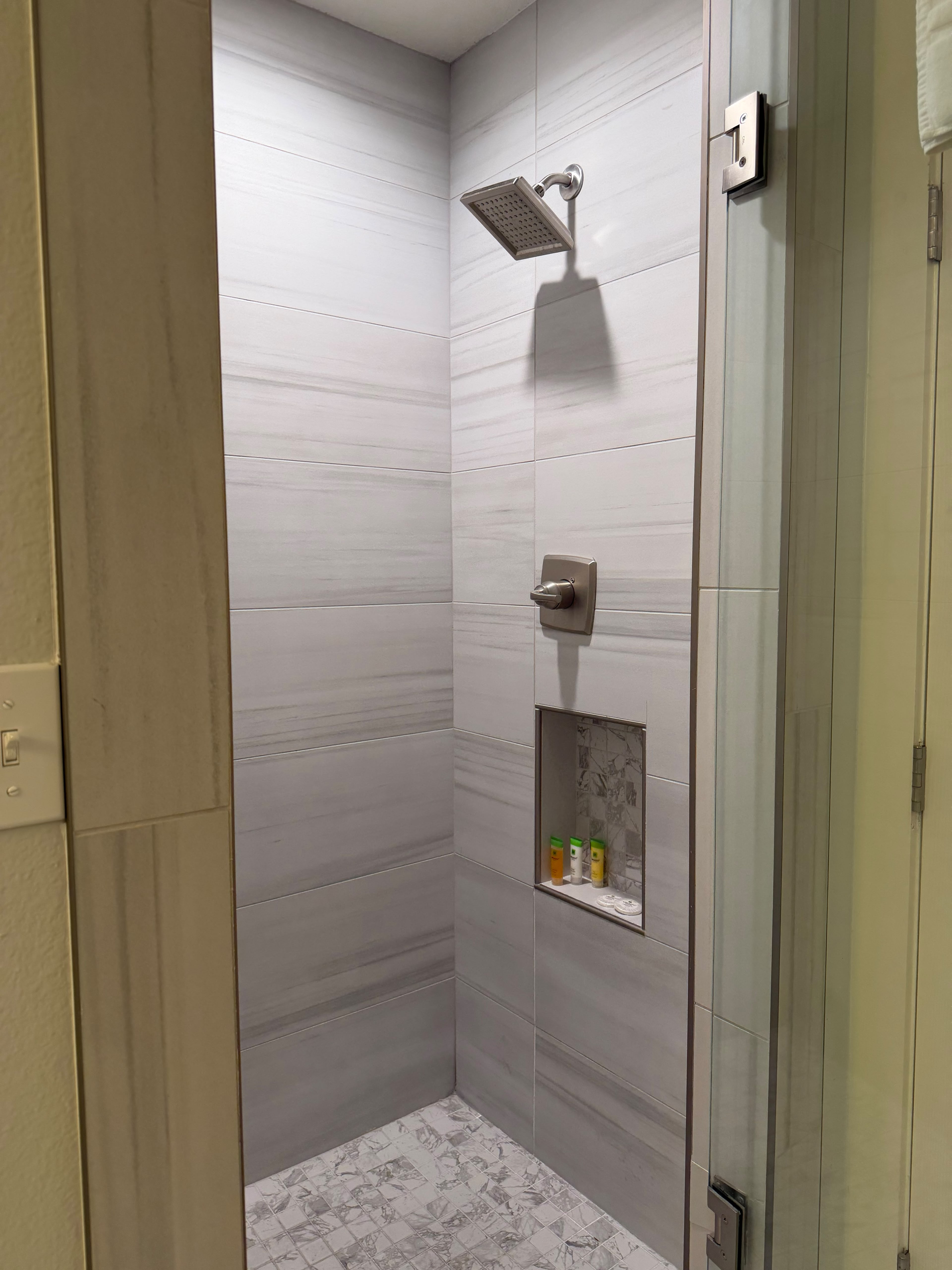Modern tiled walk-in shower with glass door and built-in storage