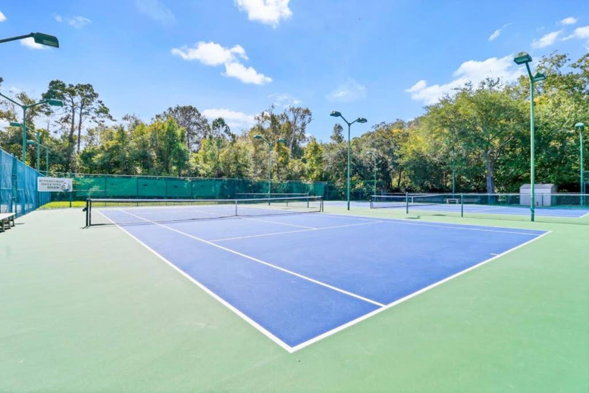 Resort-style tennis courts with lighting and a private, tree-lined setting