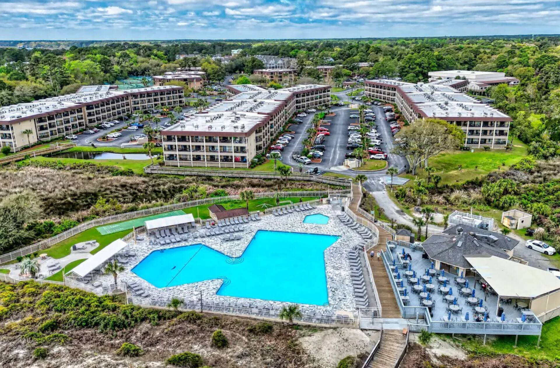 Resort-style retreat with expansive pool deck, lounge seating, and lush grounds