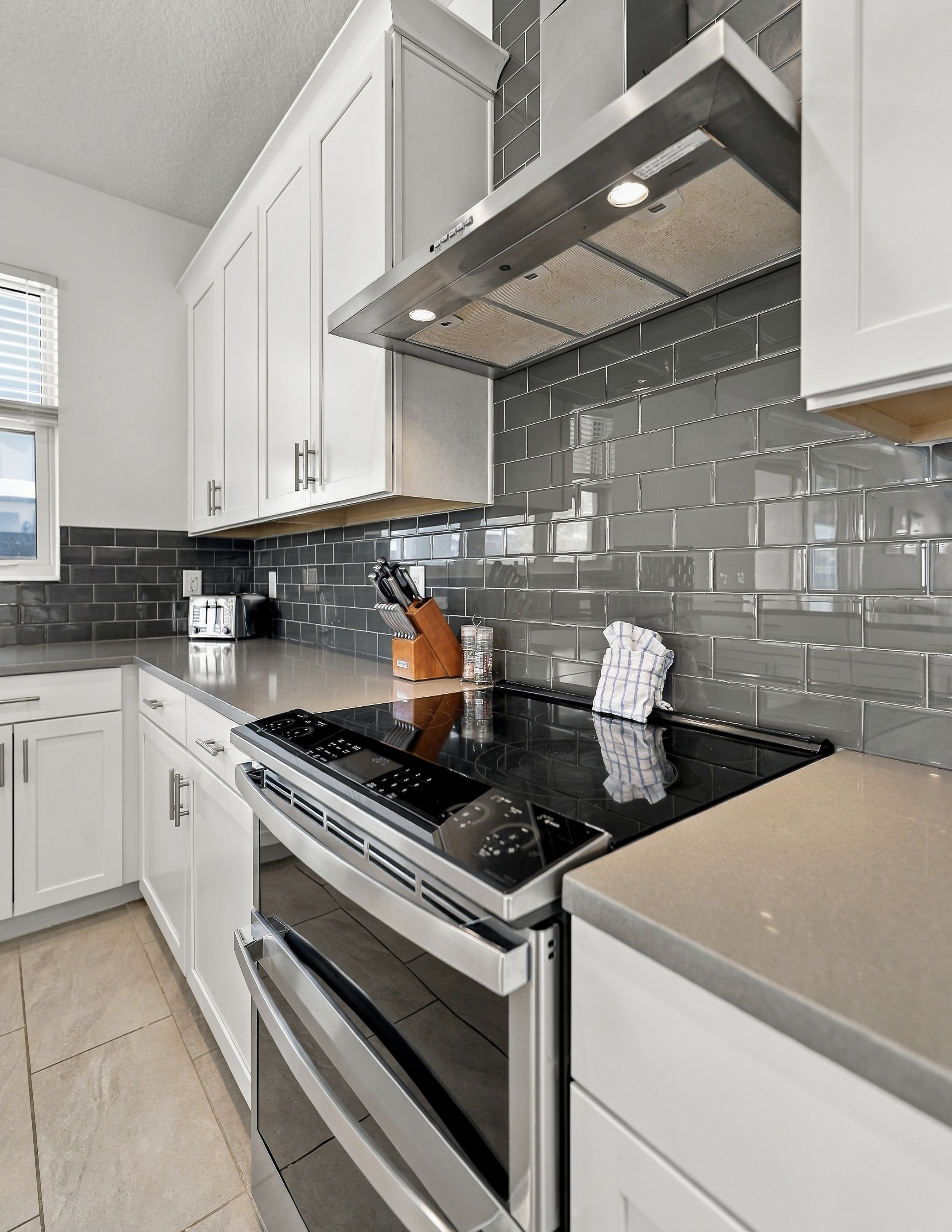 Modern kitchen with stainless appliances and sleek gray tile backsplash