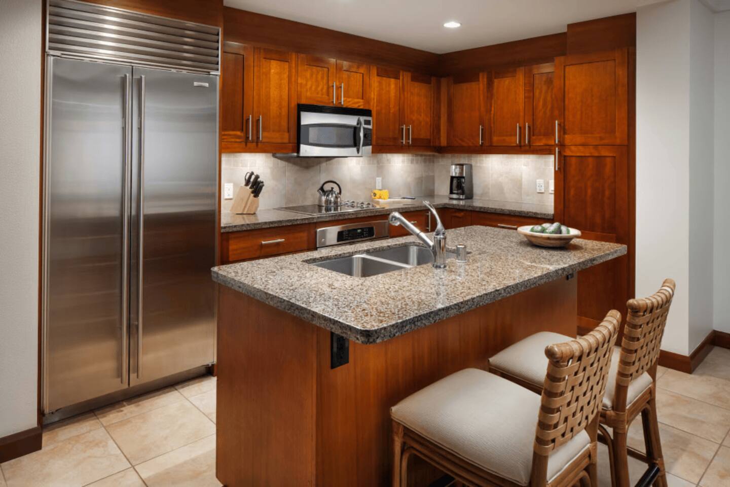 Upscale kitchen with granite island, bar seating, and stainless appliances