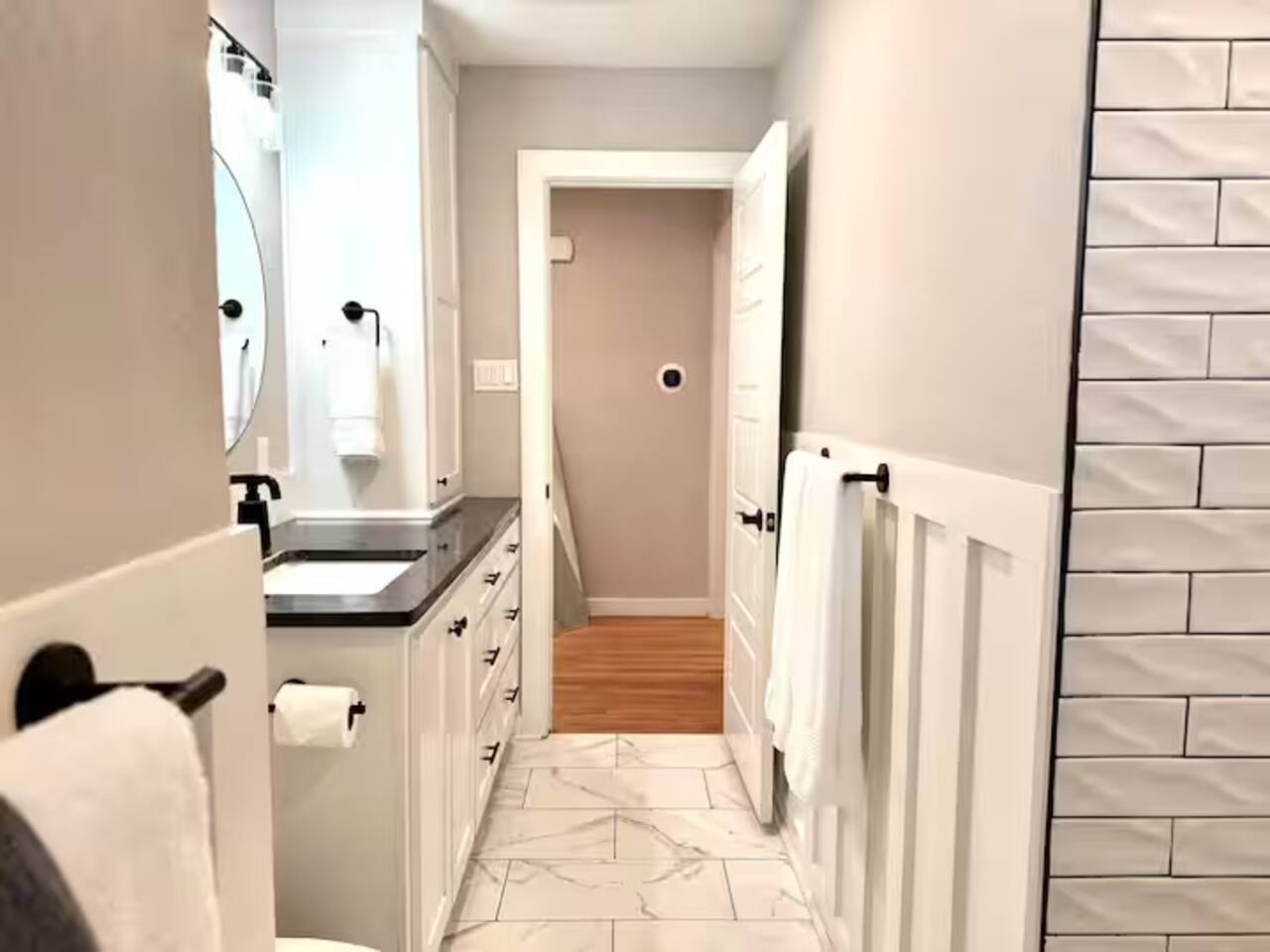 Refresh in this spa-like sanctuary featuring elegant marble-style flooring, chic wainscoting, and premium matte black fixtures. Enjoy a bright, clean space complete with complimentary toiletries for a high-end stay.