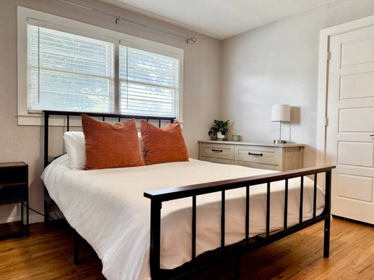 Sleep soundly in this serene, sunlit bedroom! Featuring a plush queen bed with chic accent pillows, large windows for natural light, and a minimalist design, it’s the ultimate cozy retreat for a restful night’s stay.