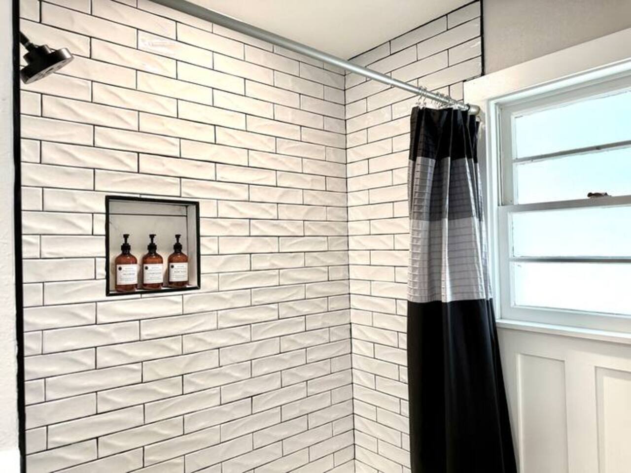 Refresh in this spa-like sanctuary featuring elegant marble-style flooring, chic wainscoting, and premium matte black fixtures. Enjoy a bright, clean space with complimentary luxury toiletries.