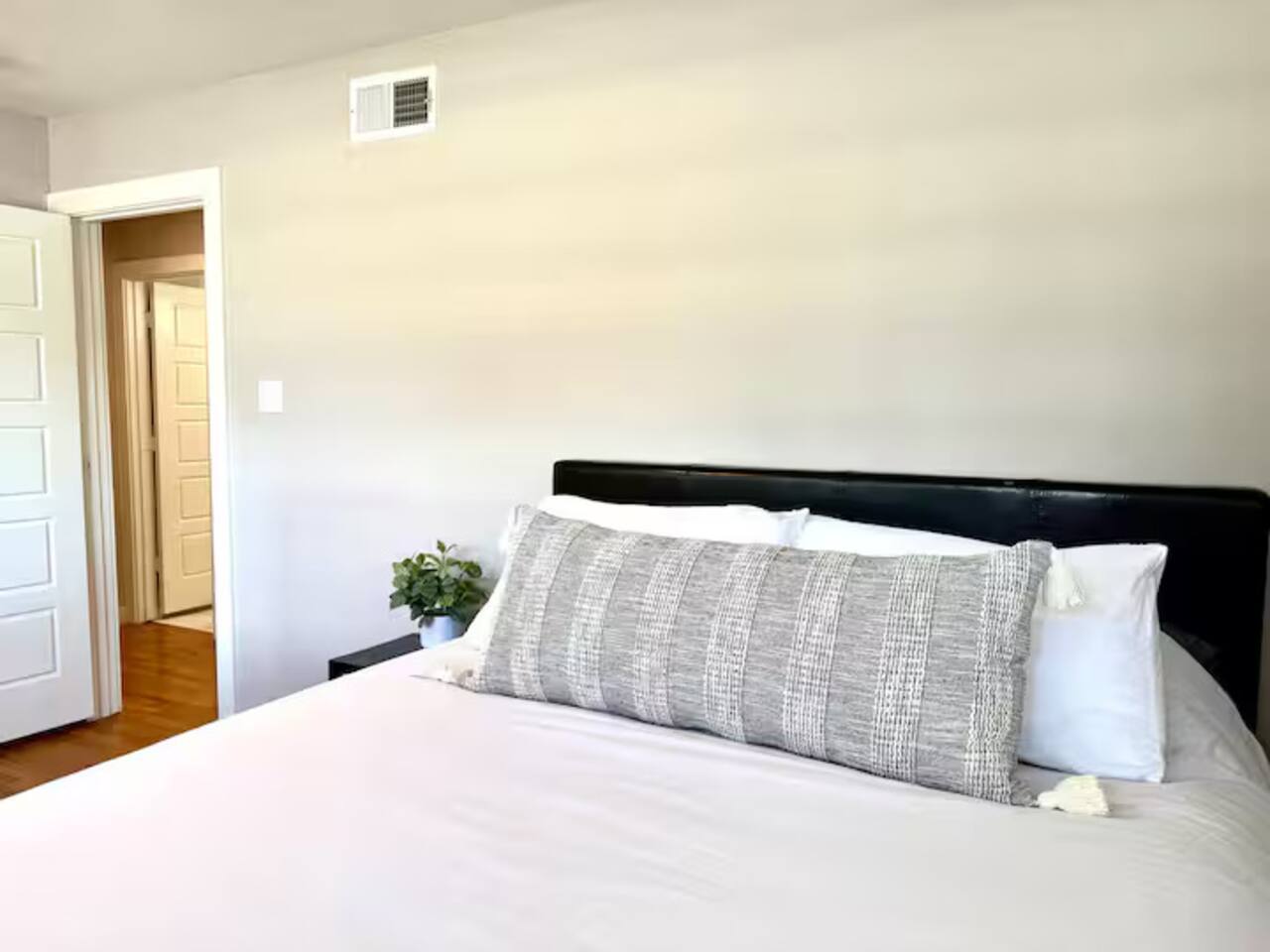 Unwind in this serene, minimalist bedroom designed for ultimate rest. Featuring a plush queen bed with crisp linens, warm hardwood floors, and a calming neutral palette, it’s a peaceful sanctuary for your stay.
