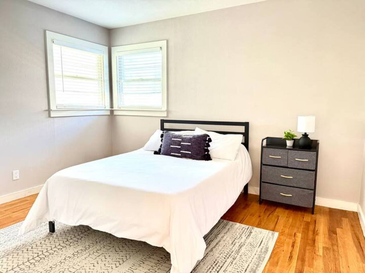 Relax in this serene, light-filled bedroom. It features a plush bed with crisp linens, a dedicated workspace with a desk, and a large smart TV for all your streaming favorites.