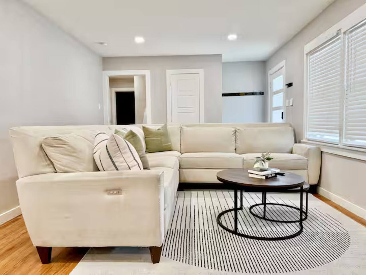 Relax in this bright, spacious living area featuring a plush sectional sofa and modern decor. With warm wood floors and large windows, it’s the perfect spot to unwind after a day of exploring.
