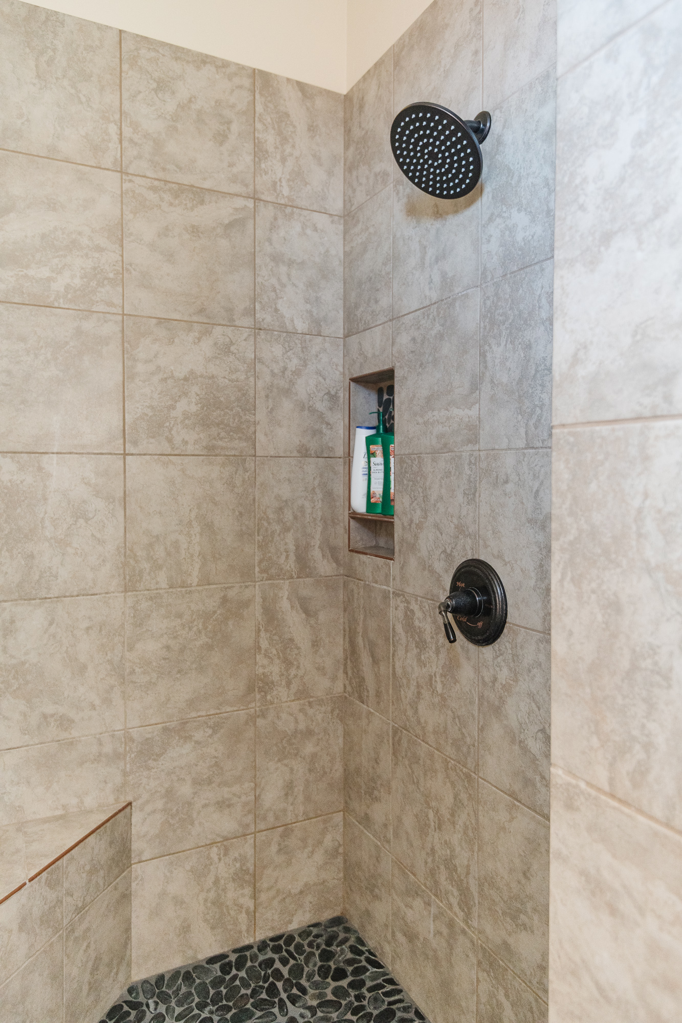 Spa-like tiled walk-in shower with rainfall head and pebble floor