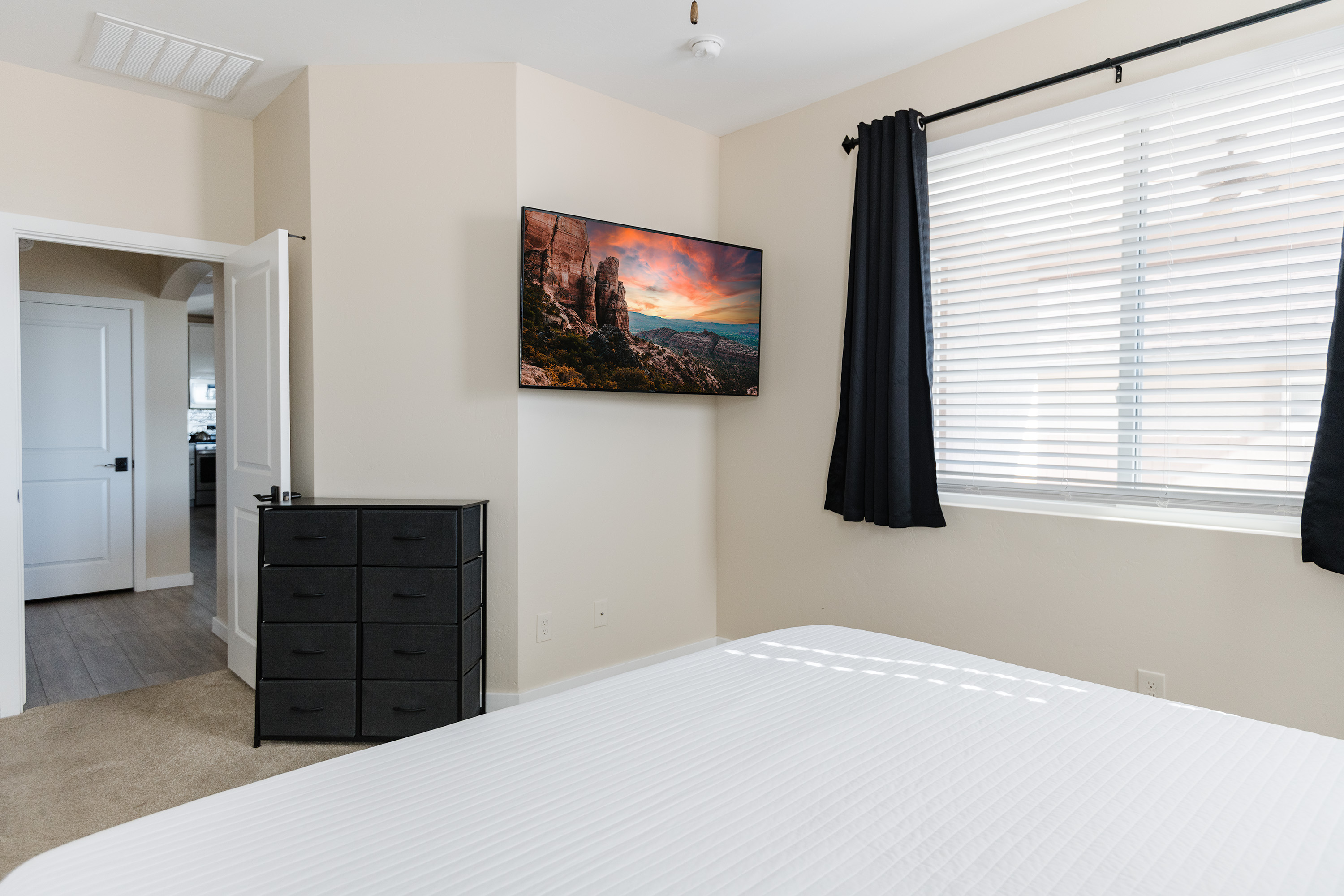 Bright, comfortable bedroom with TV, dresser, and natural light