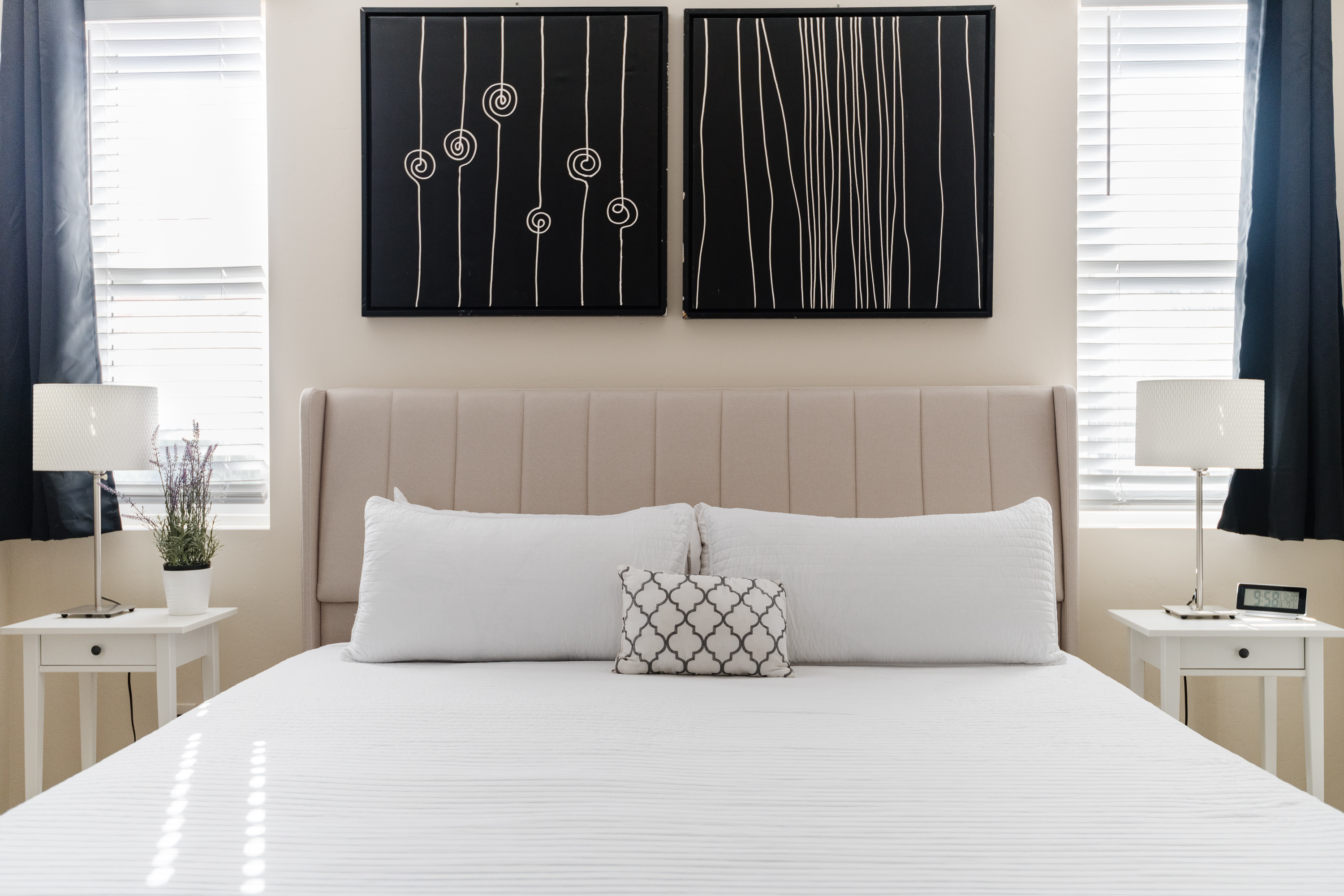 Bright, modern bedroom with plush bedding and elegant, symmetrical decor