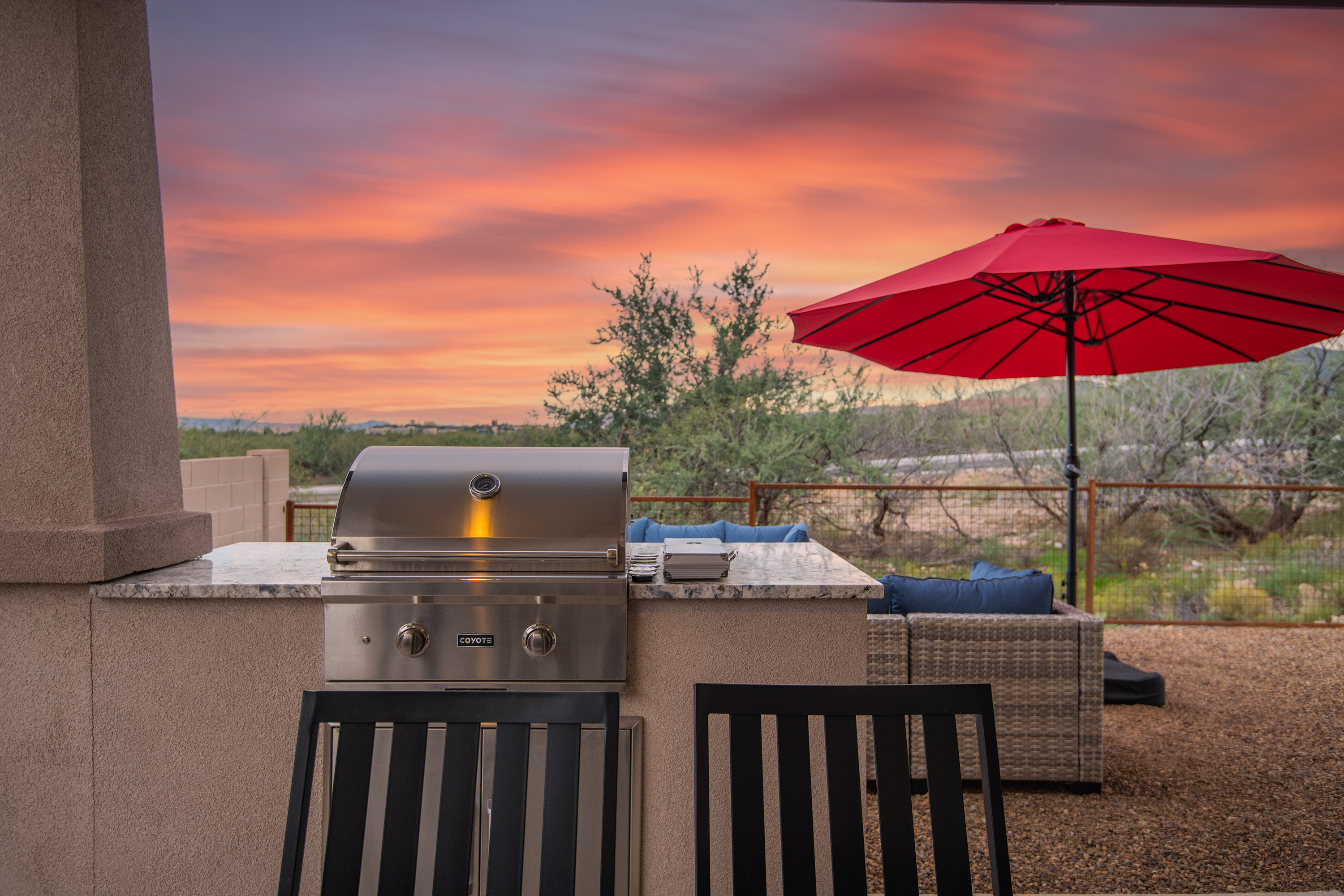 Sunset patio with built-in grill, lounge seating, and desert views